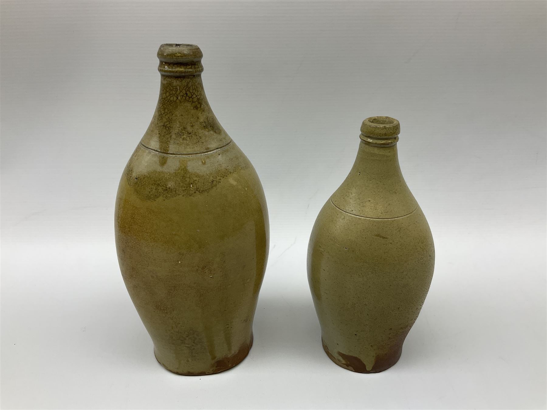  19th century salt glazed stoneware gin bottle impressed John Shaw, Red Lion Vaults, Whitefriargate, Hull of bulbous oval form H27cm and another with impressed label for J. Christie Mytongate Hull (2)  