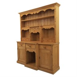 20th century country style waxed pine housekeeper’s cupboard, upper section with moulded cornice, shaped aprons and open shelving around central drawer arrangement, the lower section fitted with three drawers and two cupboards with panelled doors, raised on a plinth base