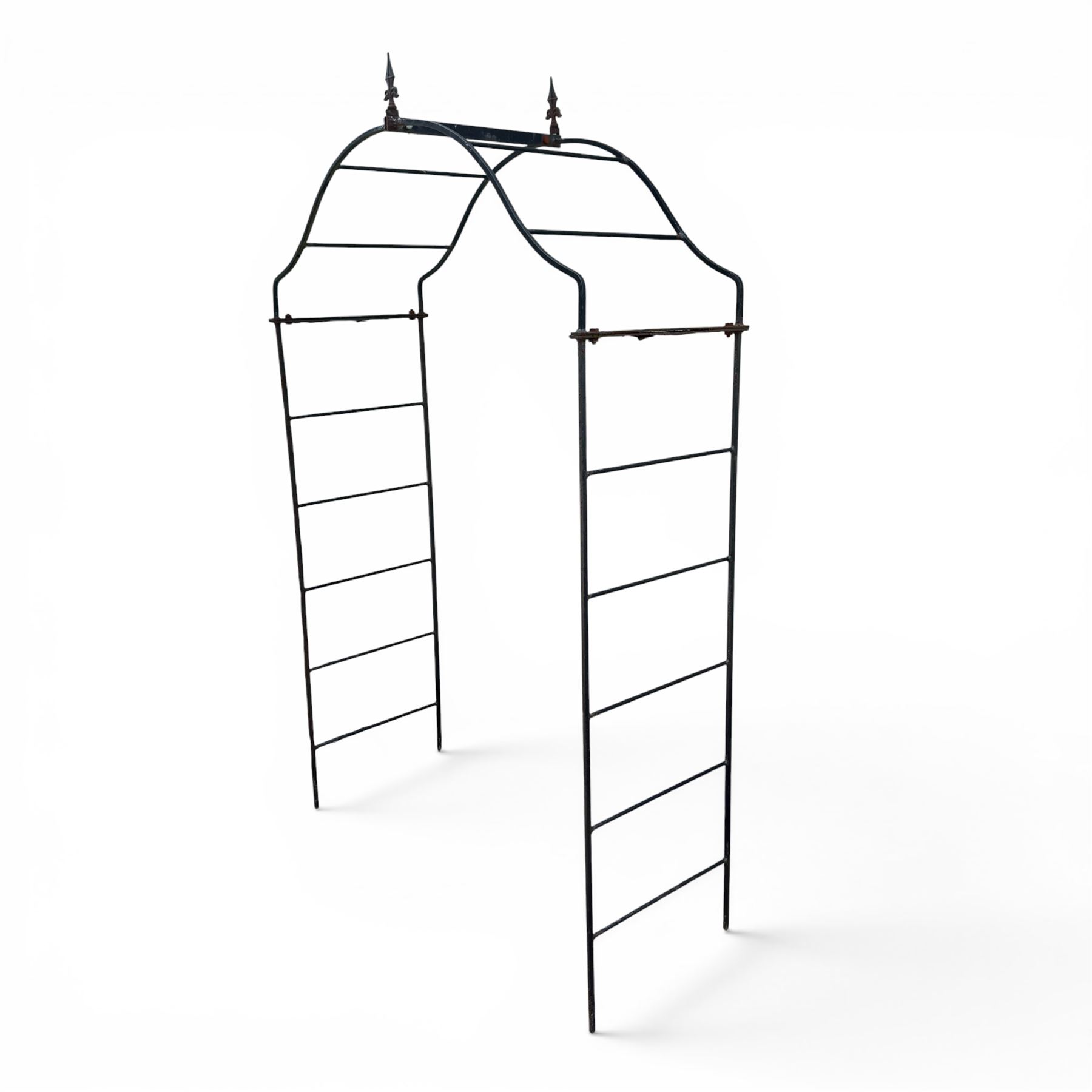 Antique wrought iron strapwork garden arch, with scroll form arched top with spearhead finials, over integral side trellis panels, in distressed black-painted finish