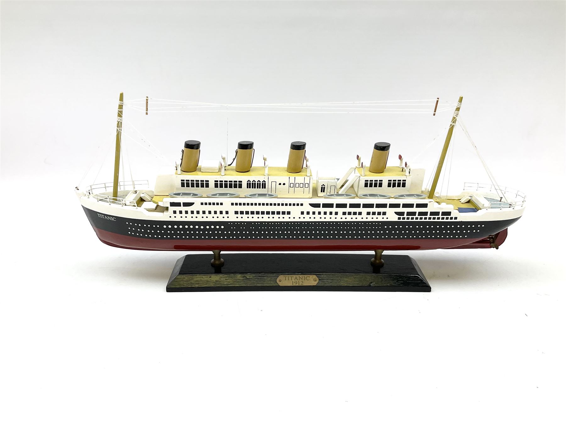 Wooden model of RMS Titanic, on a fixed black stand bearing plaque inscribed 'Titanic 1912', L54cm, H22cm, together with model of a sloop, gaff rigged on stand bearing plaque inscribed 'Sloop' L32cm, H42cm; and model of a fishing trawler on a stand bearing plaque inscribed 'Chalutier' L35cm, H28cm (3)
