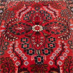 Two Persian rugs, the larger with a crimson field decorated with three linked indigo medallions amongst flowering tendrils, shaped floral spandrels and an indigo palmette border, (161cm x 129cm), the smaller with a crimson field centred by an ivory rosette amongst stylised flowering plants, within a dark floral border, (114cm x 79cm) (2)