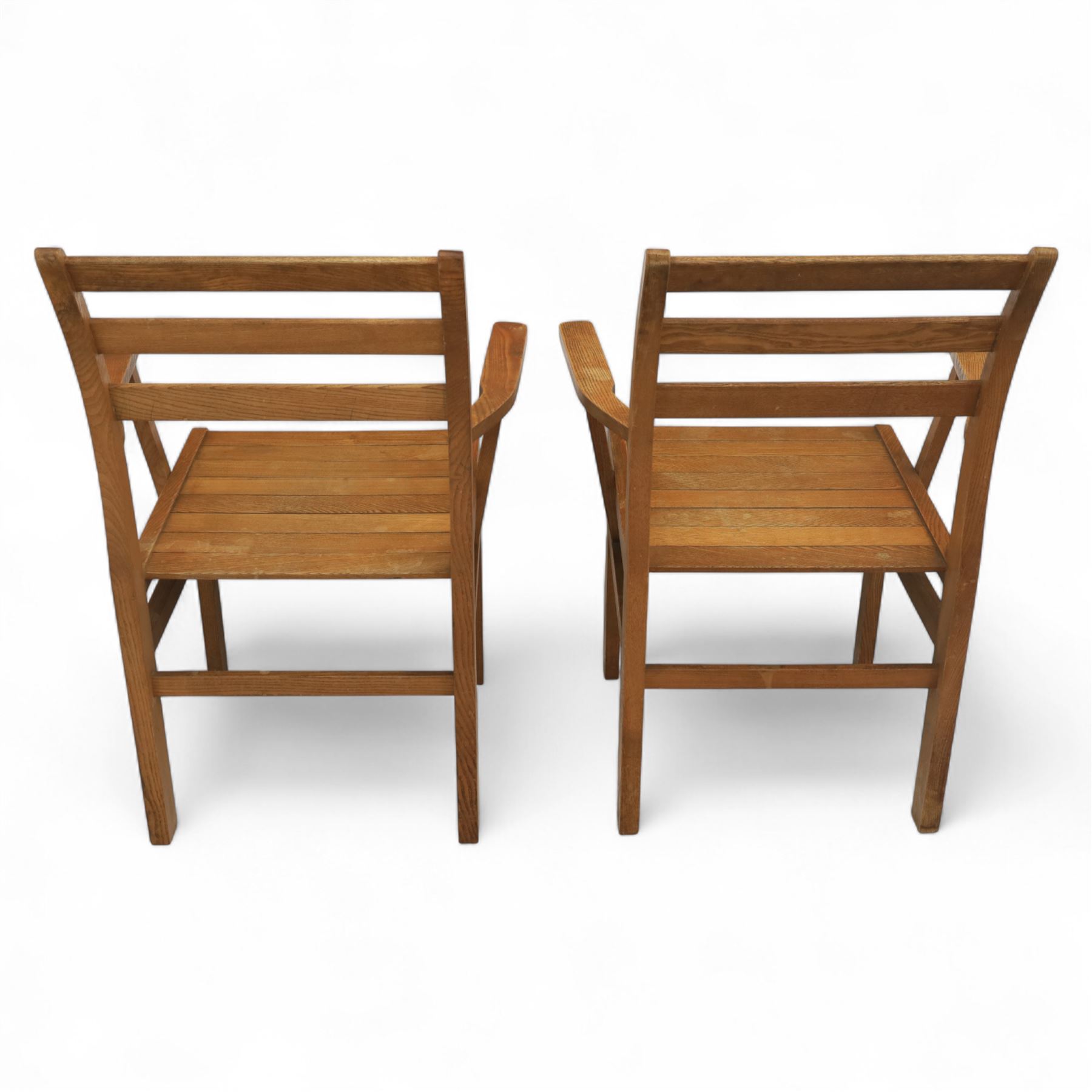 Treske of Thirsk - solid oak refectory dining suite, rectangular top with chamfered edge over trestle base united by a central stretcher, together with six matching slat back dining chairs, including two carvers, with panelled seats and square legs united by stretchers (H 87cm, W 62cm, D 57cm)