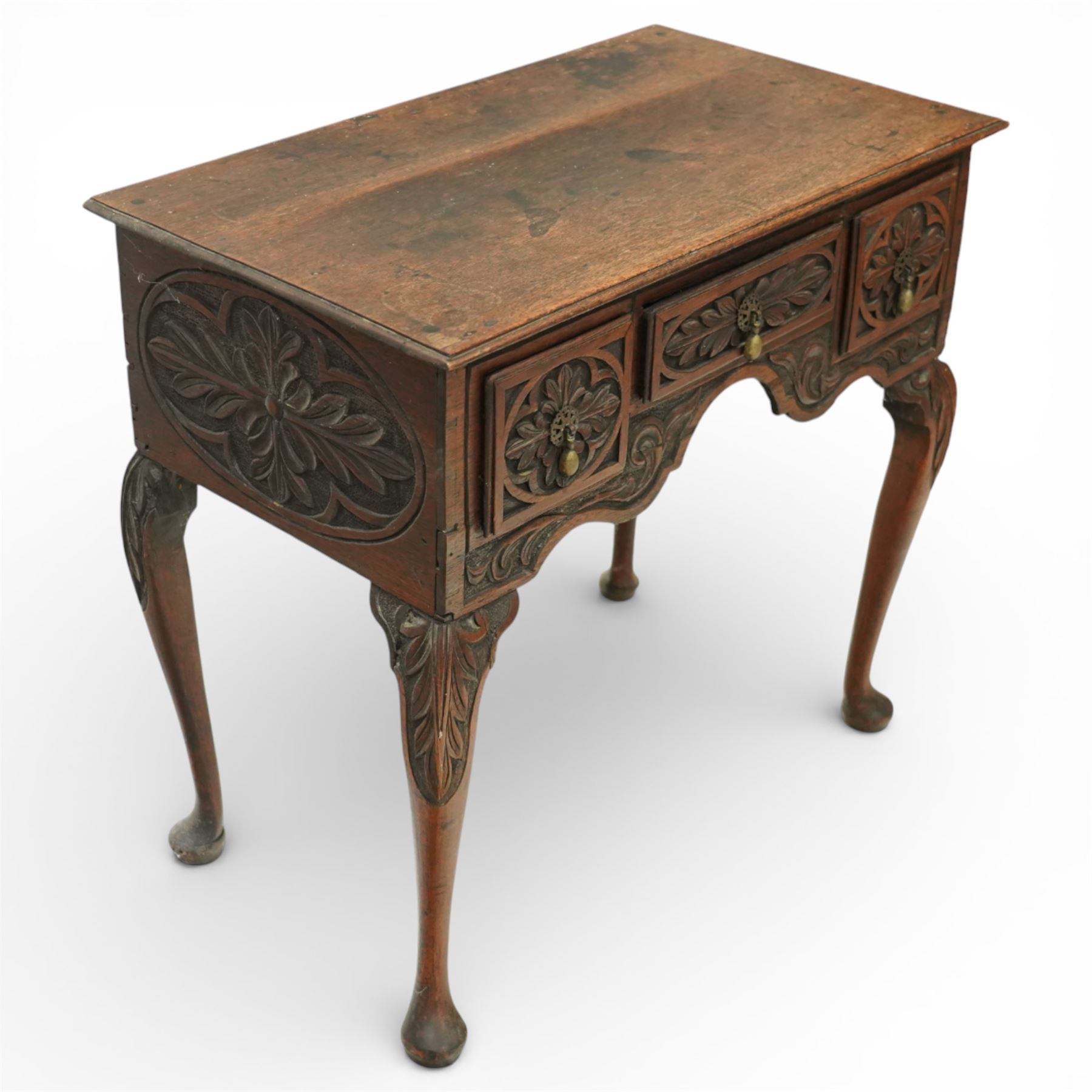 Early 20th century carved oak lowboy, rectangular moulded top above three short drawers carved with flowerhead panels and fitted with brass drop handles, shaped apron with foliate carving, raised on cabriole supports terminating in pad feet