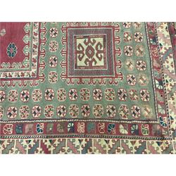 Turkish deep pink and green ground carpet, the square field with hooked borders surrounded by geometric motifs, multi-band border with overall geometric designs 