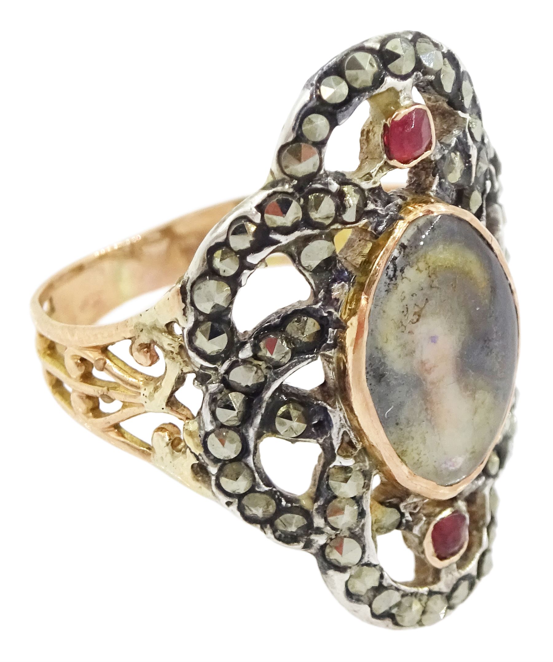 19th century gold and silver marcasite portrait ring, set with an oval miniature of a woman on ivory, under a glazed panel, with a marcasite and red stone set crossover surround, with pierced gold shoulders and reeded shank. This lot has been registered for sale under Section 10 of the APHA Ivory Act