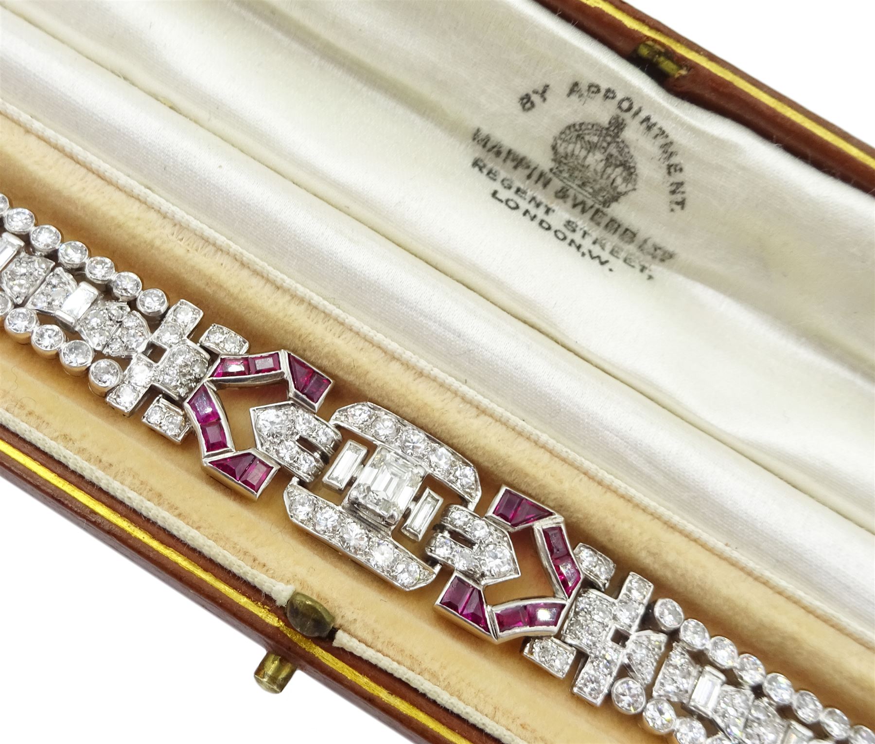 Art Deco platinum diamond and ruby bracelet, circa 1920-1930, the central panel set with a single emerald cut diamond of approx 0.55 carat, flanked by two baguette cut diamonds and old cut diamond surround, the articulated geometric design bracelet with vari-cut rubies, round and baguette cut diamonds, total diamond weight approx 7.00 carat, in Mappin & Webb silk and velvet lined box