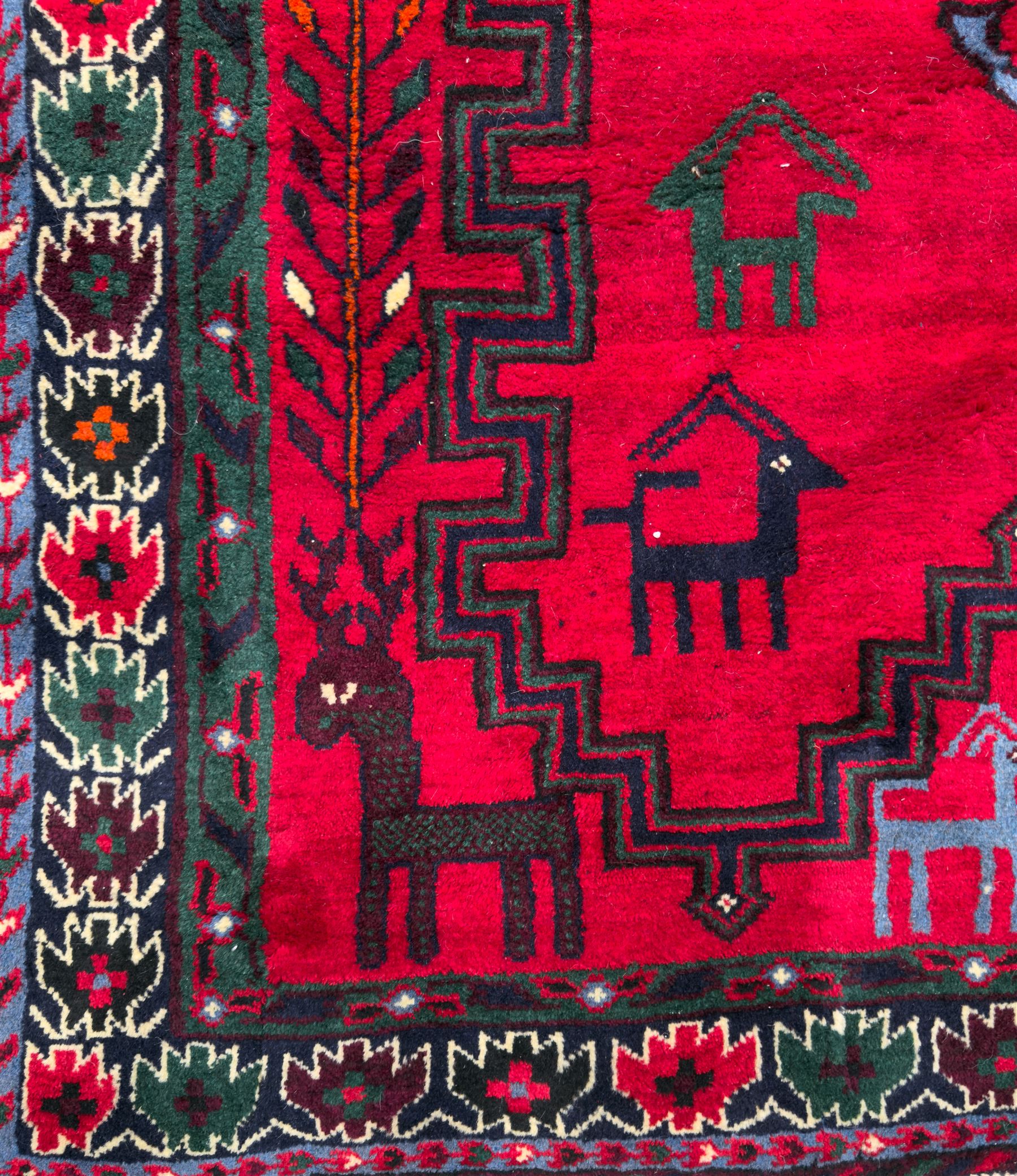 Northwestern Persian Cirjan hand-knotted carpet, madder red field with three linked stepped lozenge medallions in blue, ivory and green, flanked by angular motifs within a dark green border of serrated leaves and rosettes 