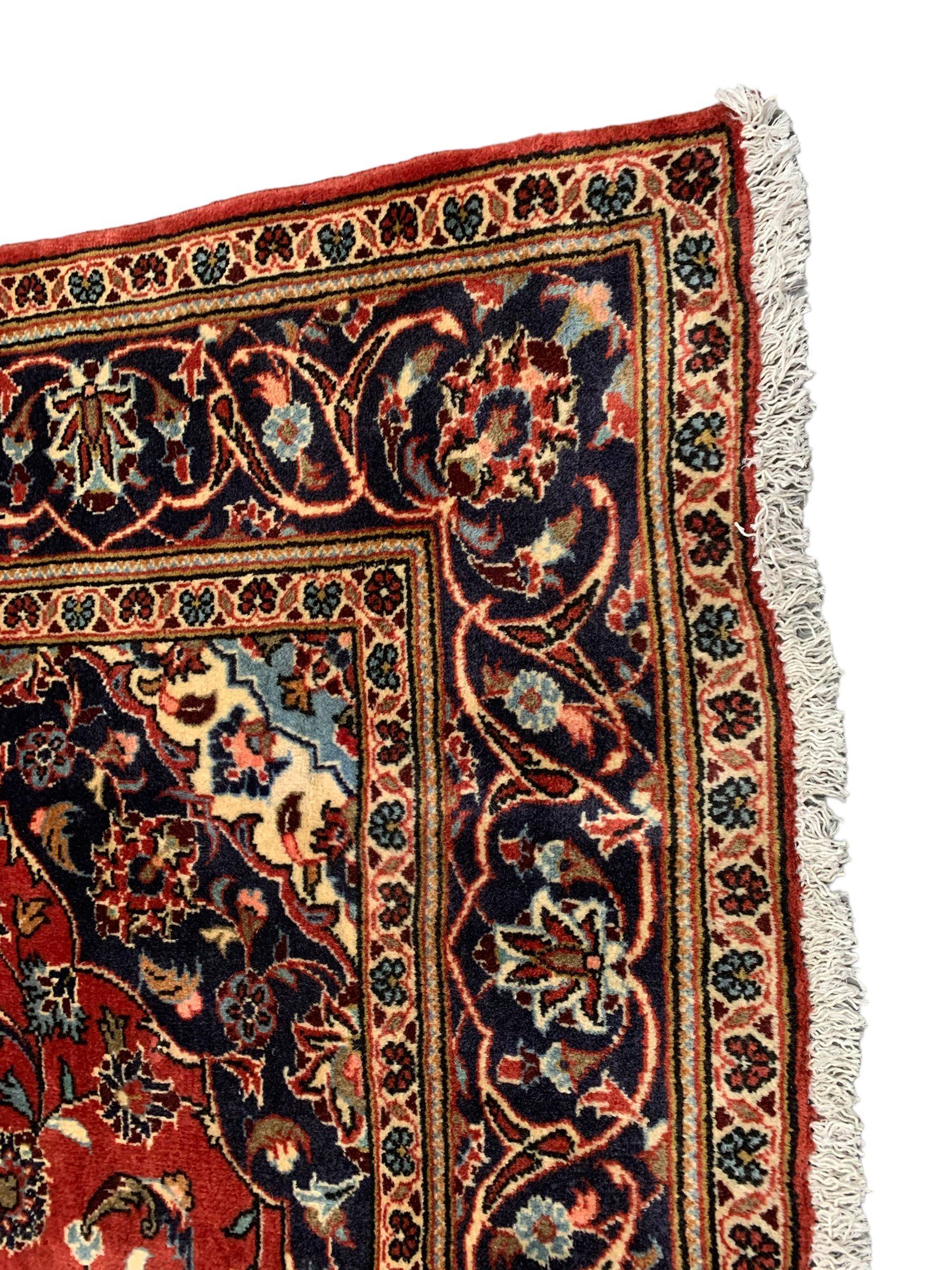 Persian Ardakan crimson ground rug, the field with shaped floral design medallion surrounded by curled leafy branches, scrolling border with stylised plant motifs