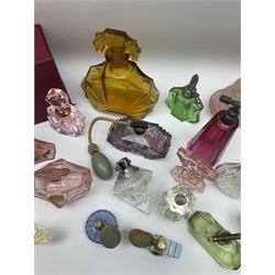 Art Deco style glass perfume bottles and atomisers, to include a large amber example with stopper of fan shape, H18cm, green glass examples with metal stoppers, and a number of other Art Deco style coloured bottles of geometric form with stoppers and mounts