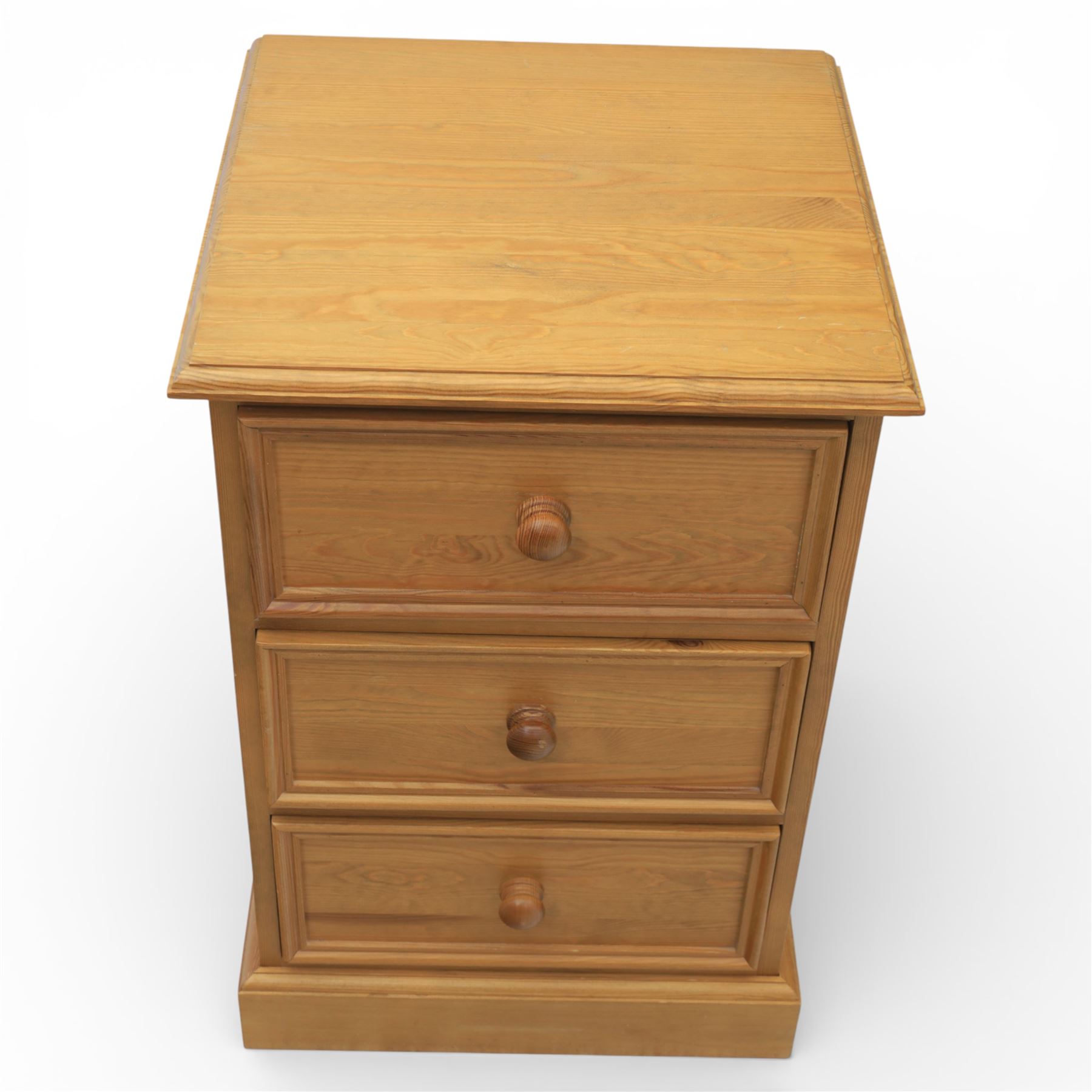 Pair of late 20th century waxed pine bedside chests, three drawers with moulded edges and turned pulls, raised on a plinth base 
