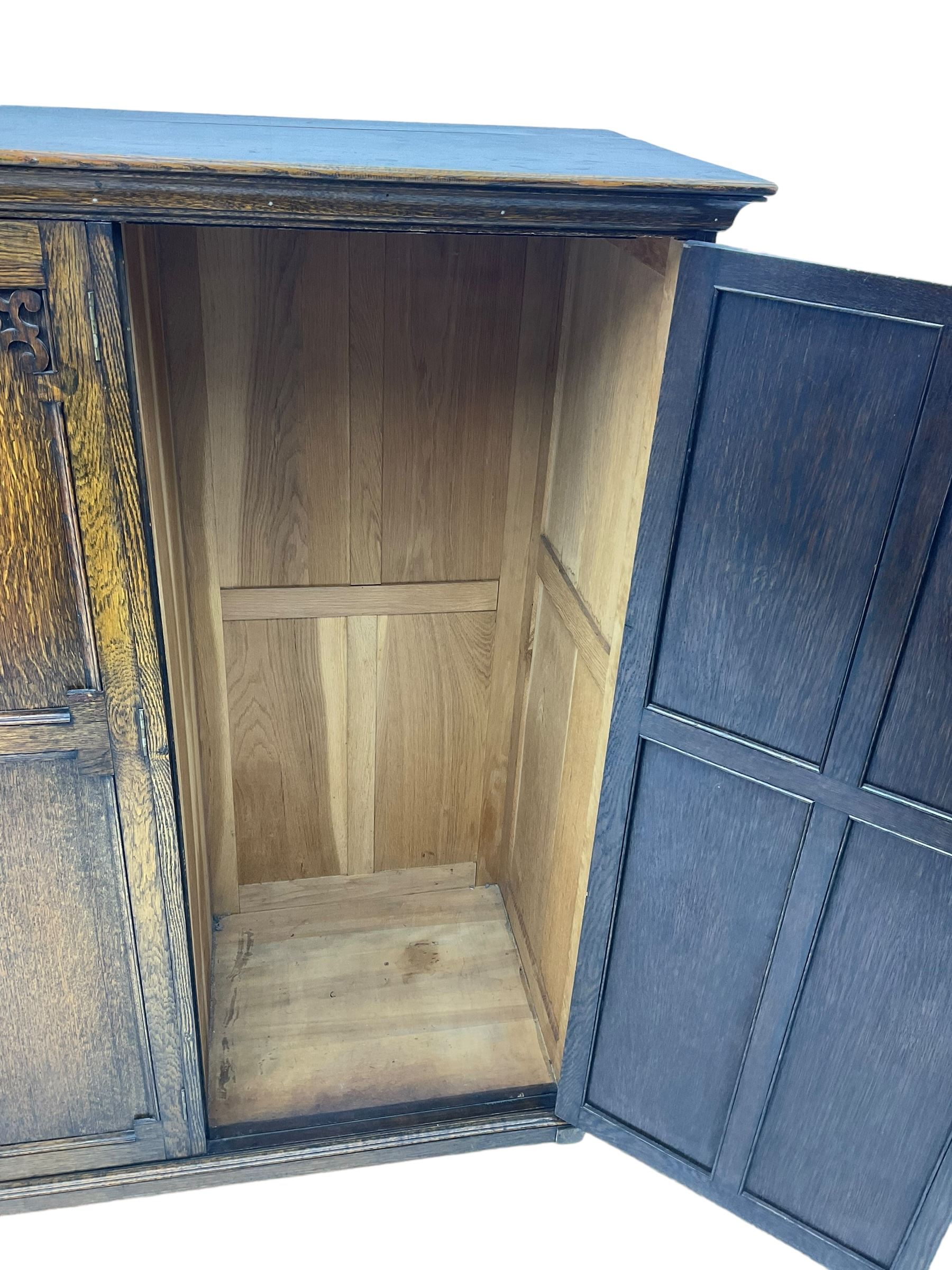 Early 20th century oak triple wardrobe, three panelled doors with geometric mouldings and fretwork spandrels, the interior fitted with slides and hanging rail