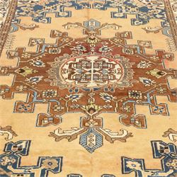 North West Persian Tafresh hand-knotted rug, pale apricot field with central stepped medallion enclosing stylized floral and angular motifs framed by indigo spandrels and multiple stylized floral borders, cotton fringe ends 