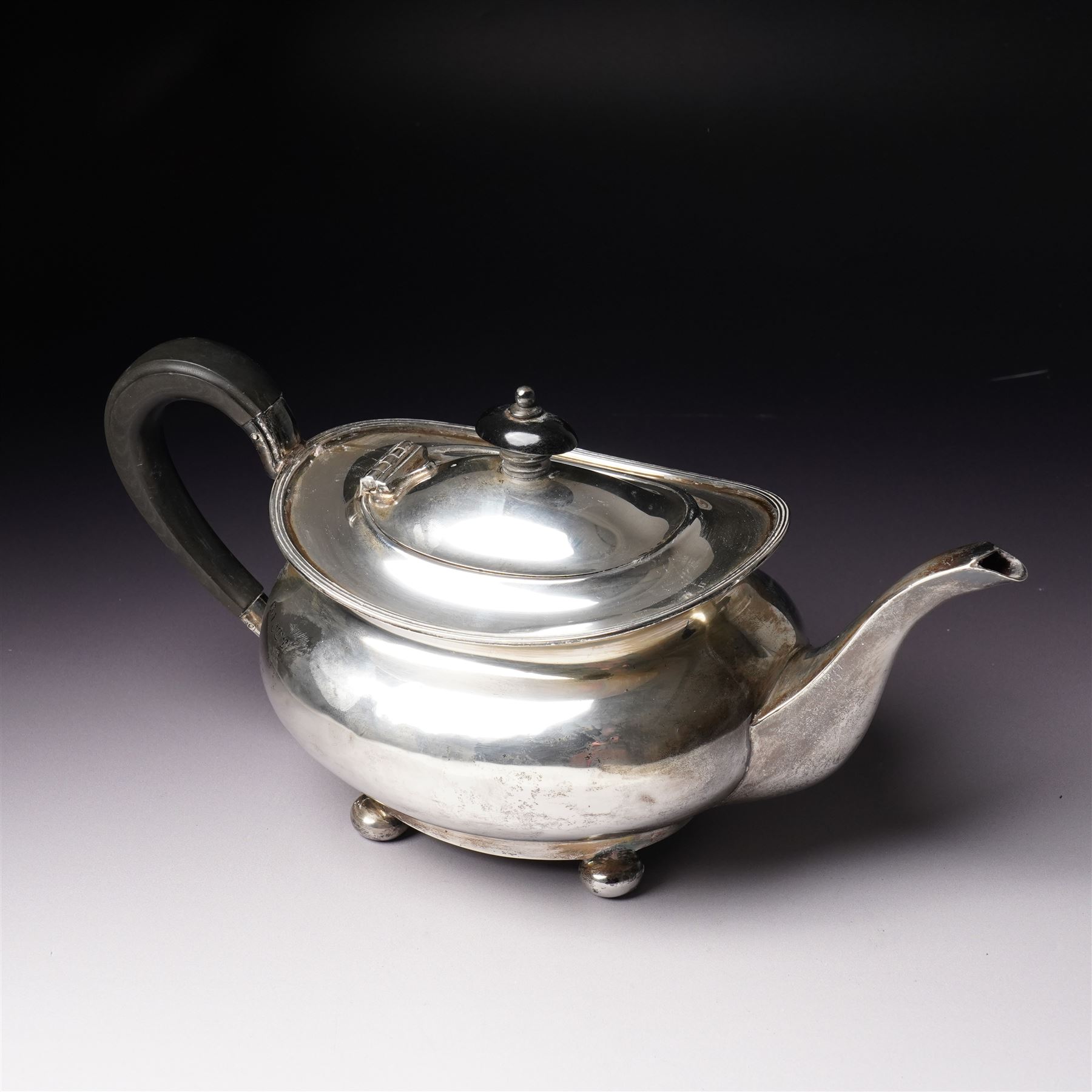 Silver tea pot of oval form with ebonised handle and lift on compressed bun feet Sheffield 1919 Maker Atkin Bros.