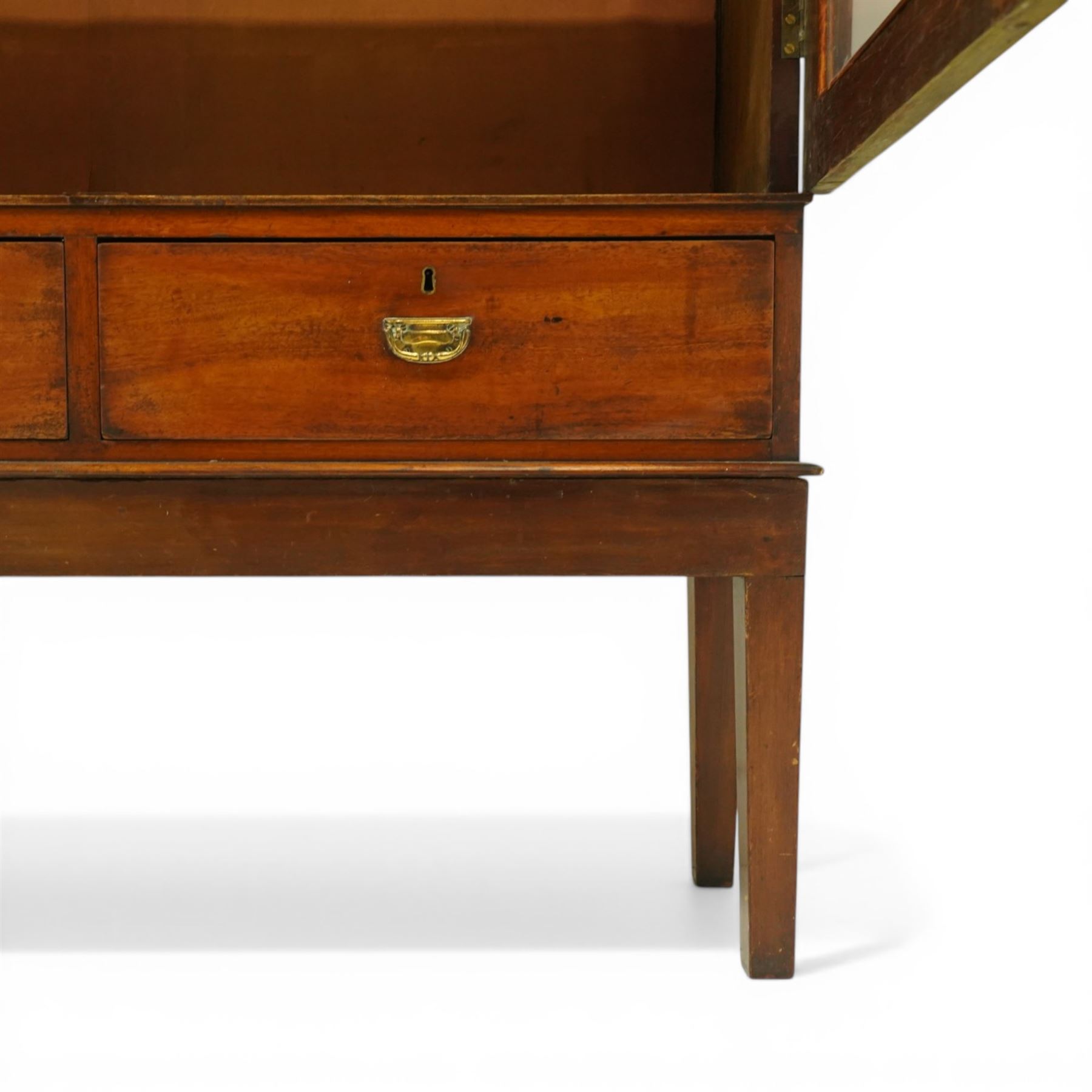 19th century mahogany enclosed bookcase on stand, projecting cornice and banded frieze over two glazed doors enclosing four adjustable shelves, fitted with two drawers to base, on square tapering supports