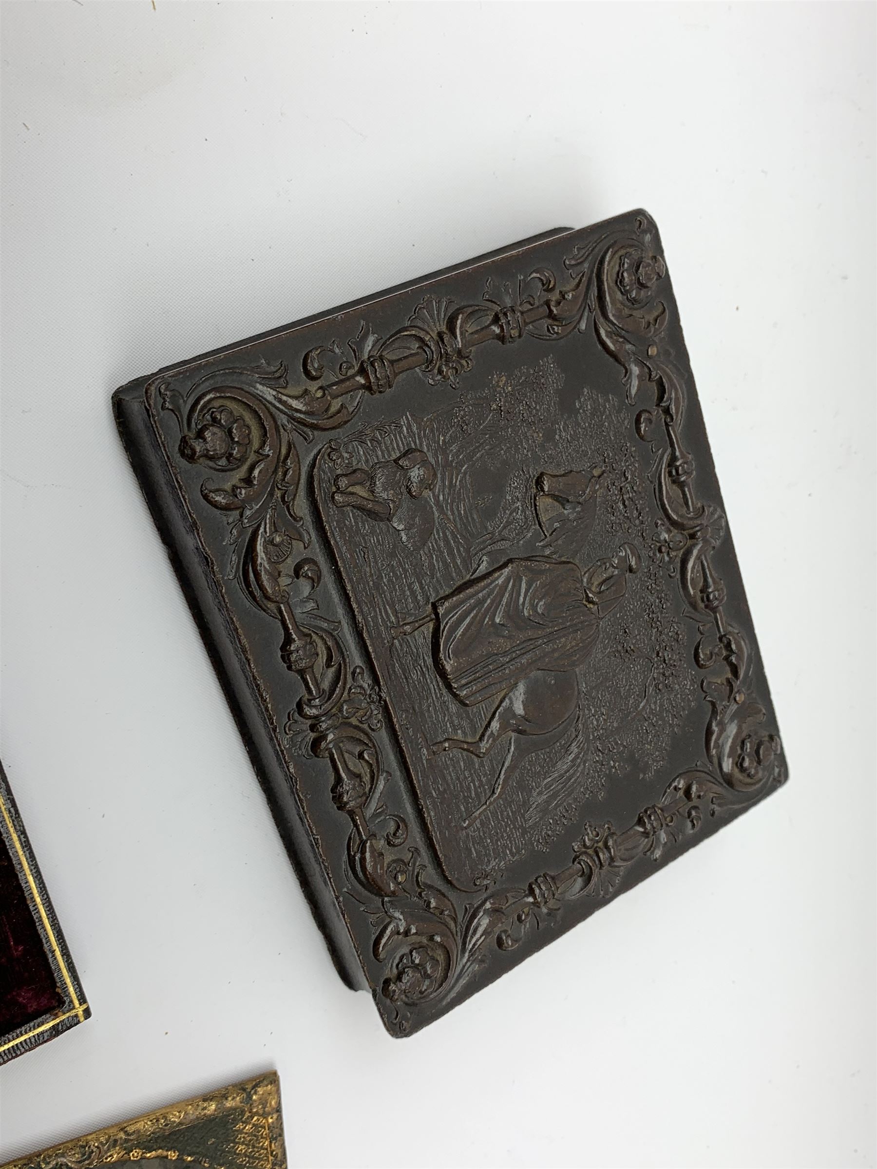 A Victorian ambrotype photograph in gilt surround and Vulcanite type Union case, decorated in low relief to front and verso with a female figure upon horseback, H12.5cm, together with a leather case daguerreotype, and a further loose example. (3).  