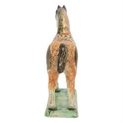 Late 18th/early 19th century Prattware pottery figure of a horse, possibly Yorkshire Potteries, circa 1790-1800, painted and sponge decorated in manganese, with blue spotted saddle secured with a yellow girth, upon a rectangular green base, H15.5cm