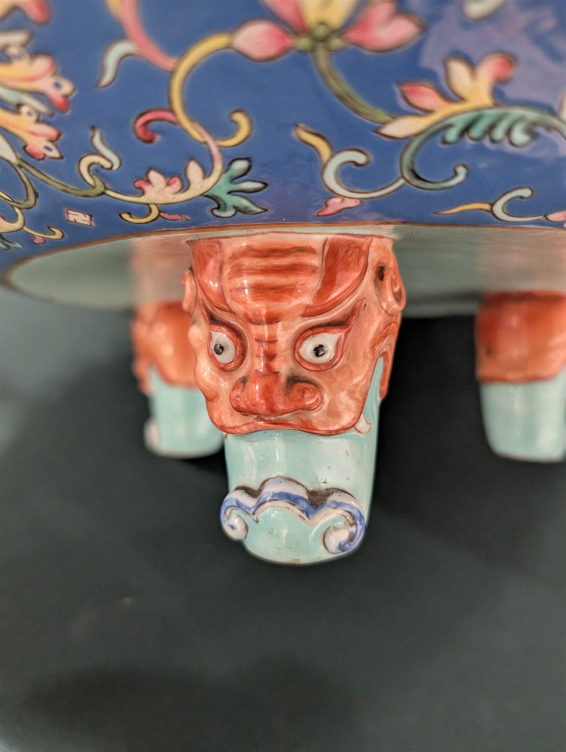 20th century Chinese footed bowl, of circular form, decorated in polychrome enamels with flowers and foliage on a cobalt blue ground, upon three grotesque mounted feet, with character marks beneath, H13cm, D38cm