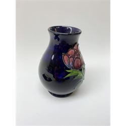 A Moorcroft pin dish and small vase, each decorated in the Anemone pattern upon a dark blue ground, each with impressed marks beneath, pin dish D11.5cm, vase H10cm.