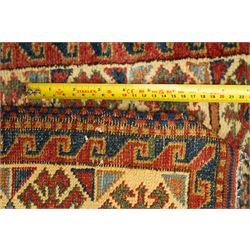 Caucasian hand-knotted runner, dark navy ground with three ivory geometric medallions surrounded by stylised flowerheads and angular motifs in madder red, green and ivory, enclosed by repeating geometric borders