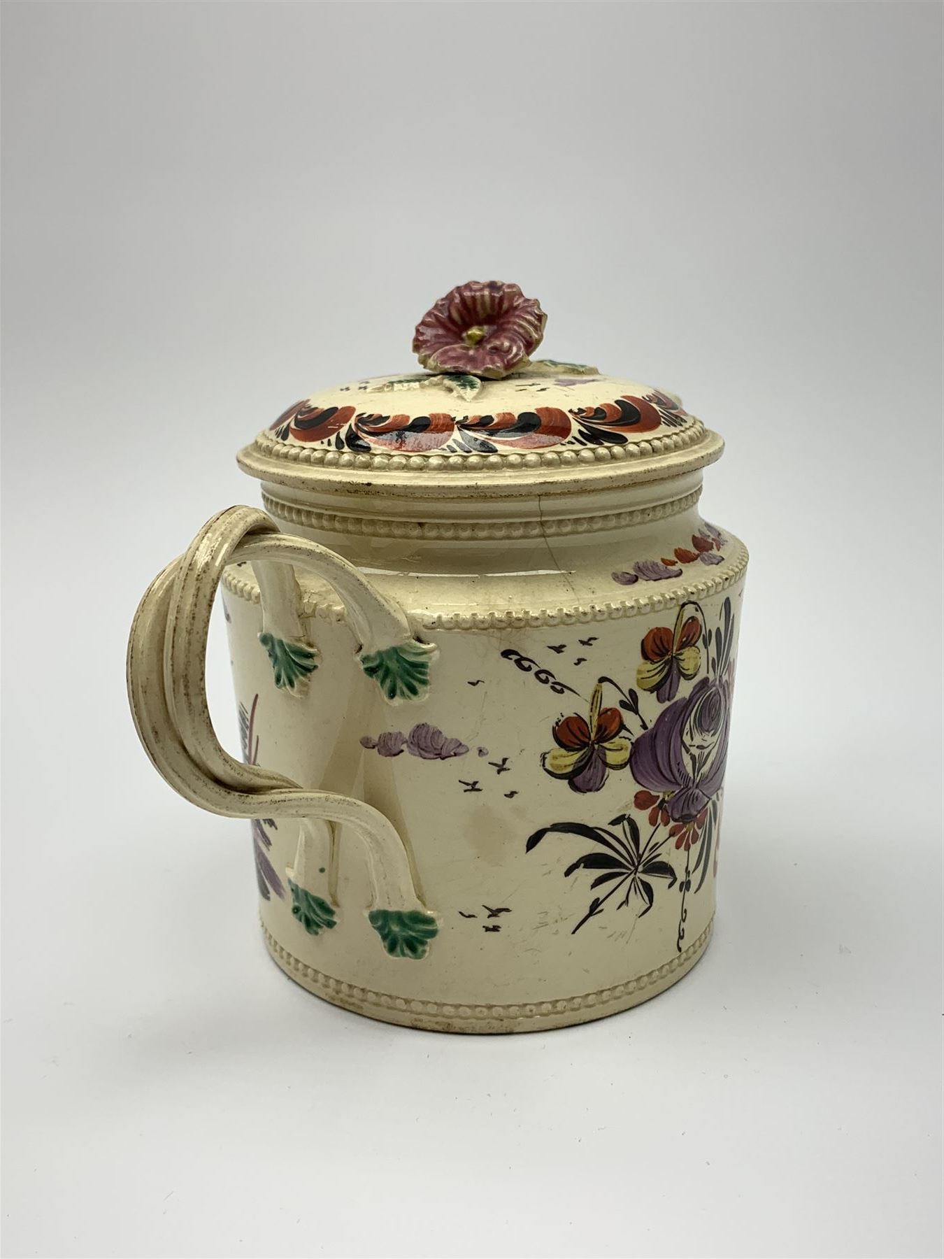 18th century creamware teapot, probably Leeds, with reeded entwined handle and floral finial to the cover, the body with hand painted polychrome decoration of figure to one side, and floral spray to the other, collectors paper label beneath inscribed Leeds Pottery, H11.5cm