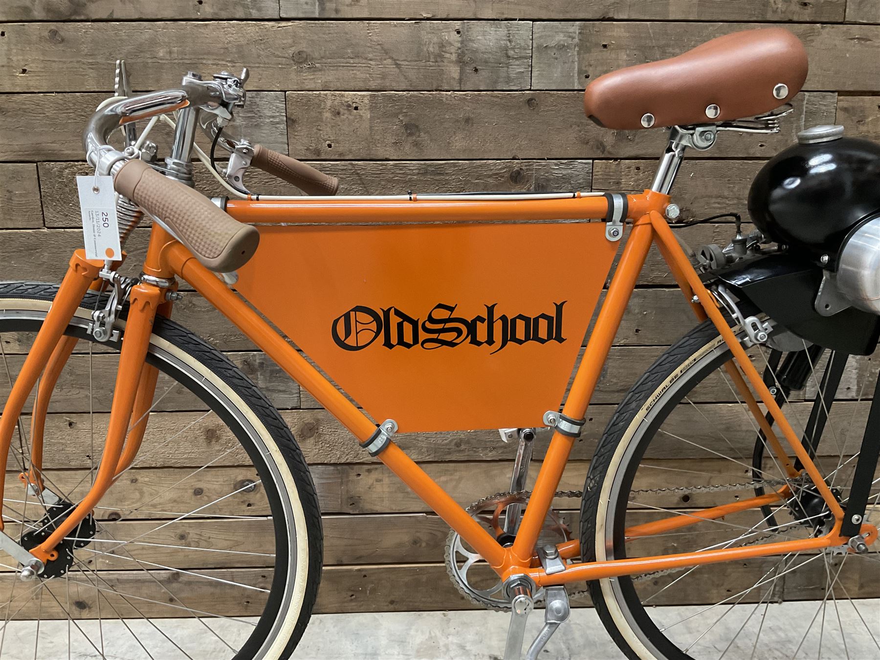 Fully restored vintage advertising bicycle with 2 stroke petrol engine, orange frame, tan leather seat