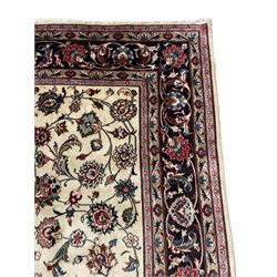 Persian ivory ground rug, the field decorated with interlaced and scrolling foliate with palmettes, the dark indigo border with stylised plant motifs surrounded by scrolled branches