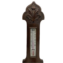 An English carved oak cased aneroid barometer with an 8'' porcelain dial, measuring barometric pressure from 26 to 31.9 inches, weather predictions written in gothic capitals and lower-case script, with a steel indicating hand and brass recording hand within a chrome bezel with a flat bevelled glass, with a spirit thermometer recording the temperature in degrees Fahrenheit and Celsius.



