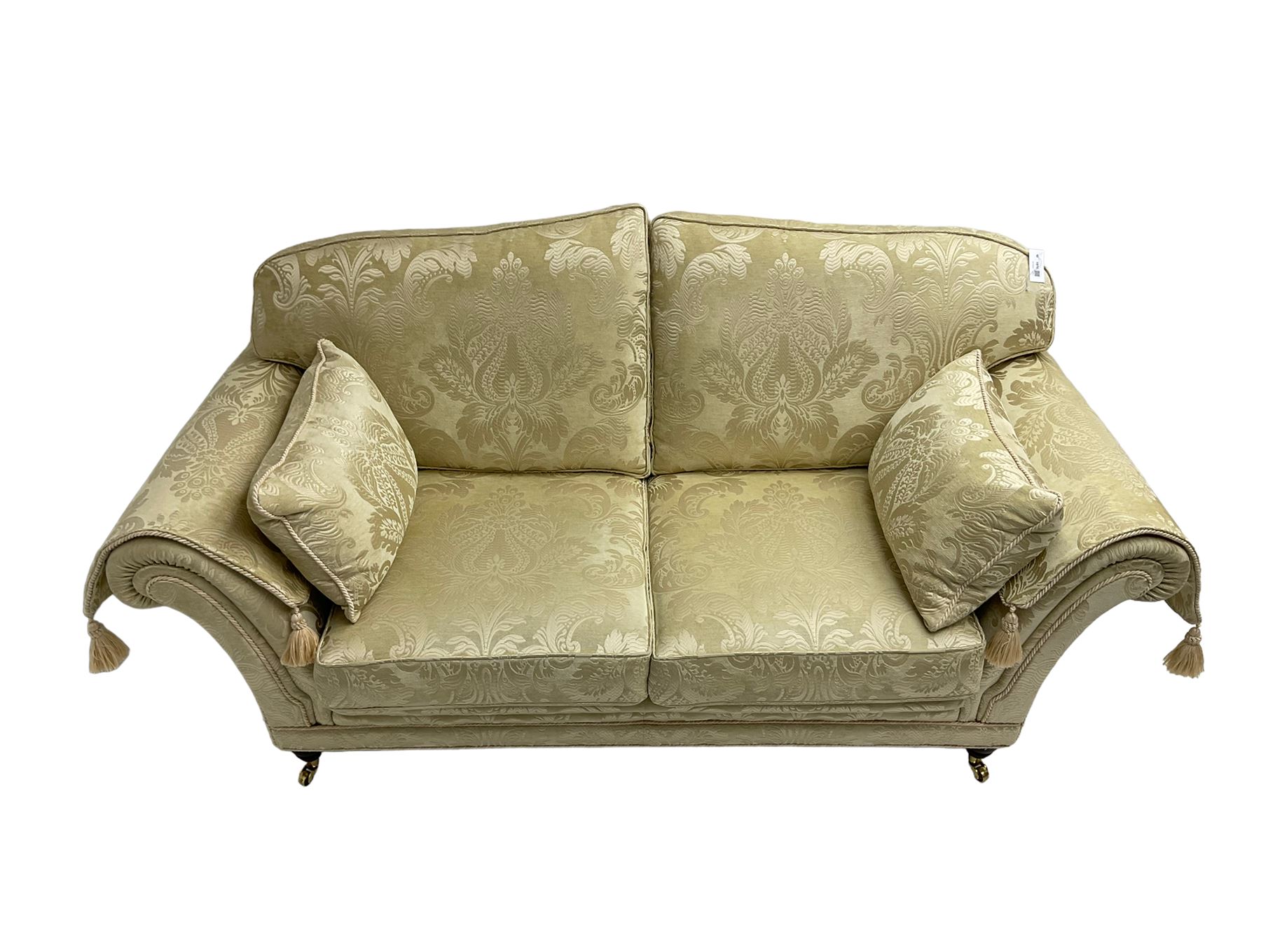 Steed Upholstery - two seat traditional shaped sofa, upholstered in cream fabric with scrolling foliate pattern, on turned front feet with brass castors, with side cushions and arm covers