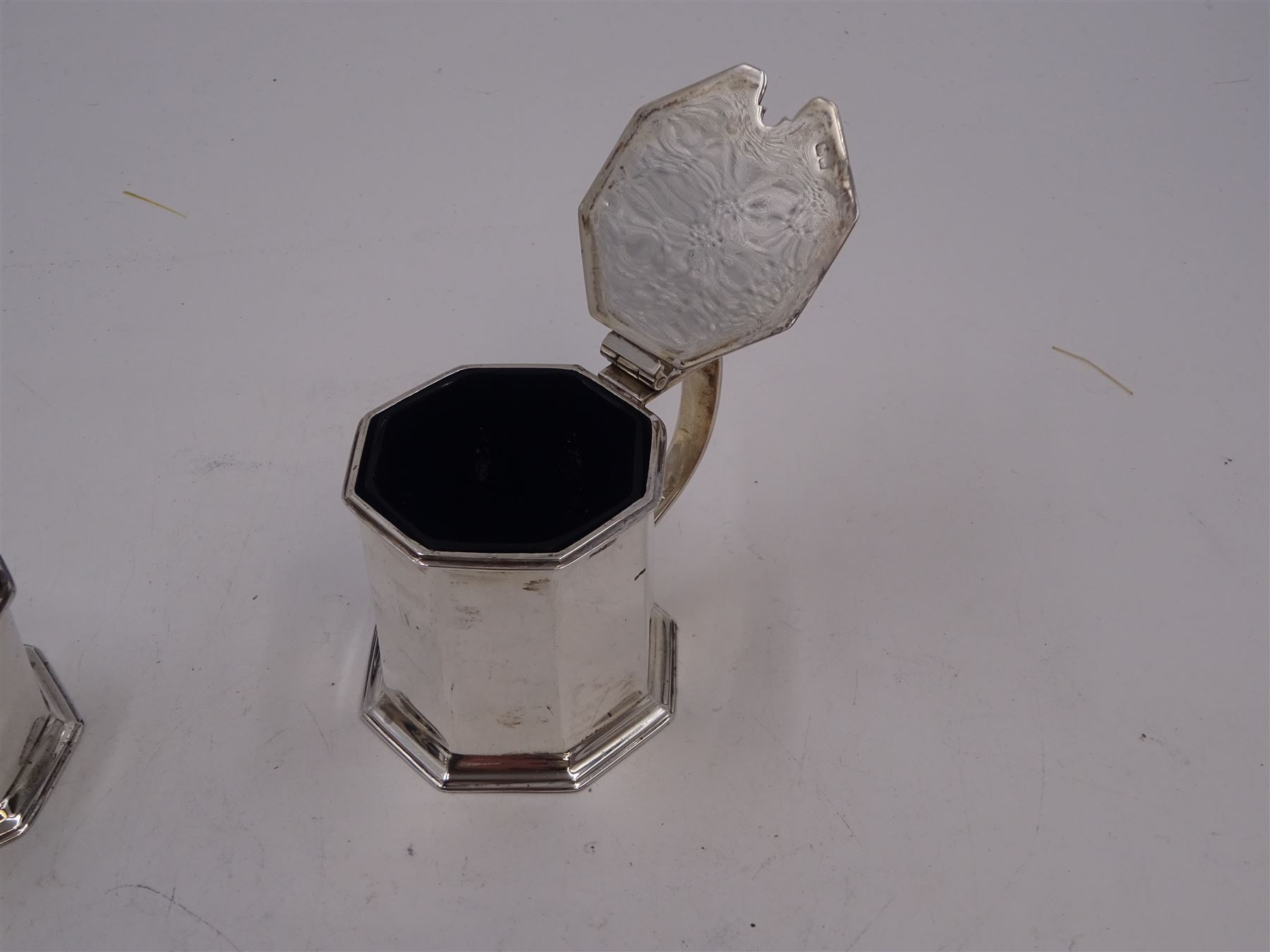 1920s silver three piece cruet set, comprising mustard pot and cover, pepper and open salt, each of faceted octagonal form, the mustard pot with pierced thumbpiece and capped handle, hallmarked Stokes & Ireland Ltd, Chester 1923 & 1924, max height 8.5cm, mustard and salt with original blue glass liners