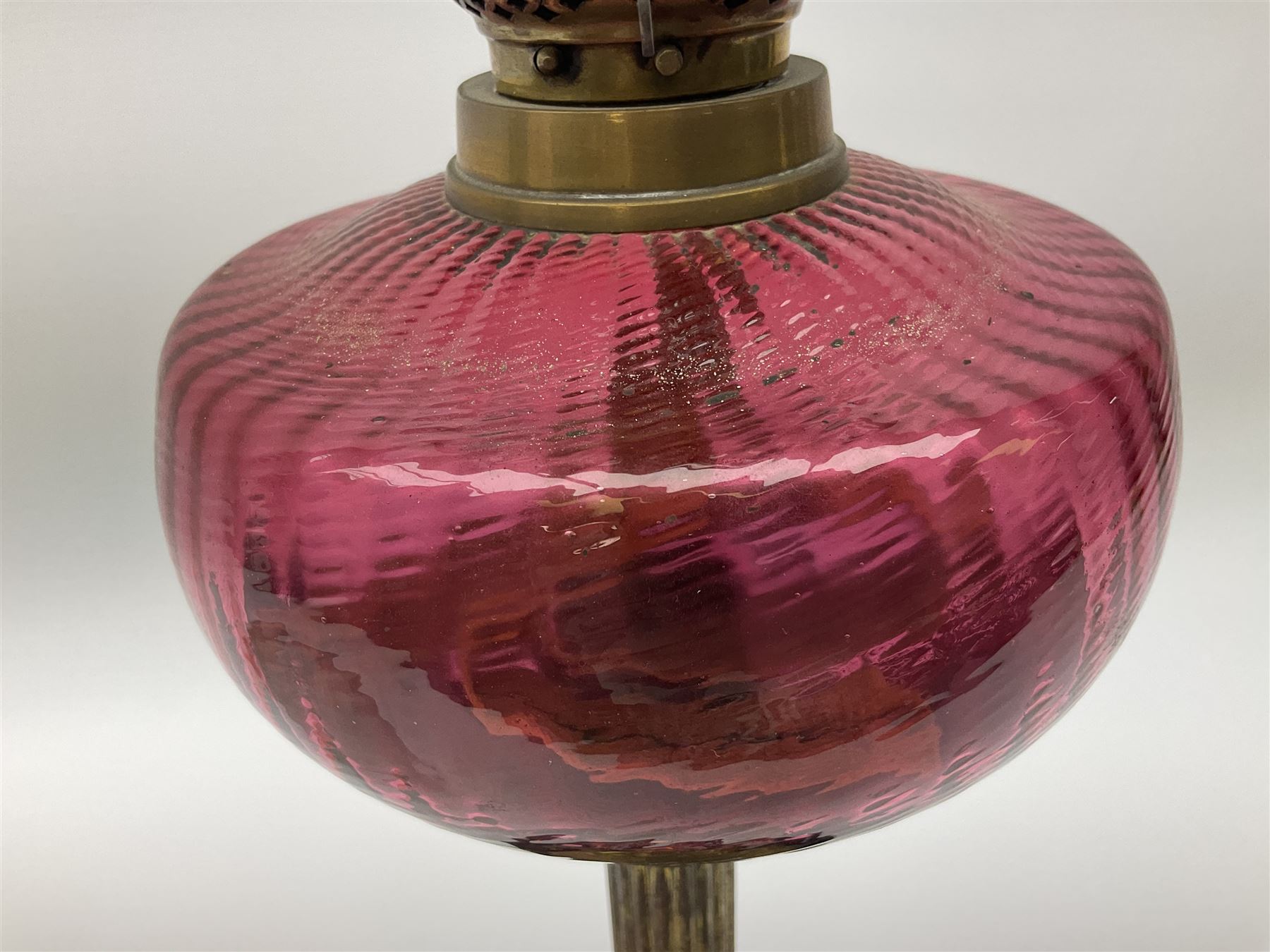 Victorian table standing oil lamp, brass fittings, cranberry glass reservoir, brass column on black enamelled ceramic base, with a frosted glass shade and clear glass chimney, H68cm