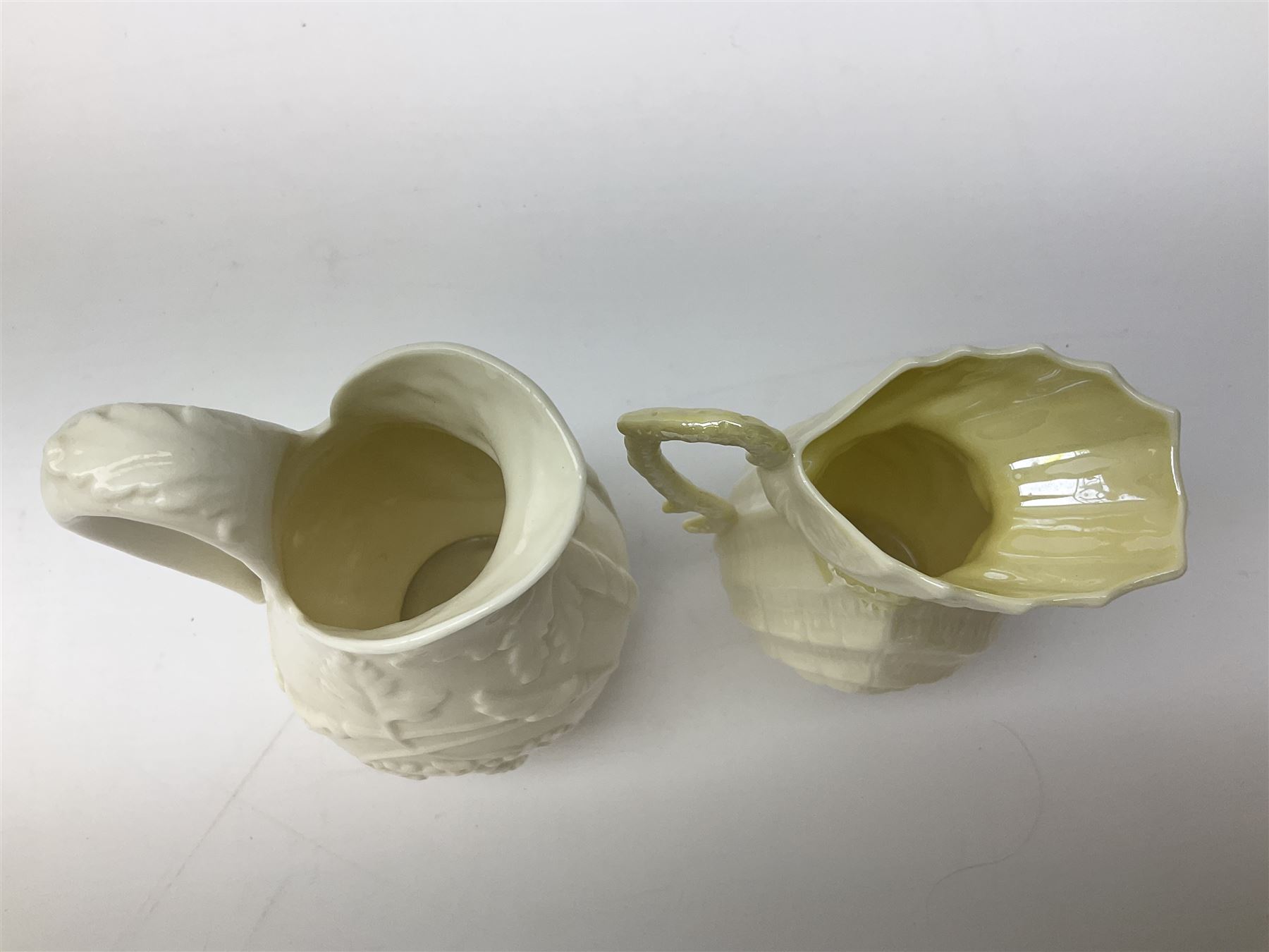 Quantity of Belleek ceramics to include mid-late 19th century jug moulded with green man mask and foliage, date code stamp for 1863-1890, together with later Belleek cornucopia shape vase, jug and other vases together with a Belleek style shell dish raised on branches, tallest H19cm