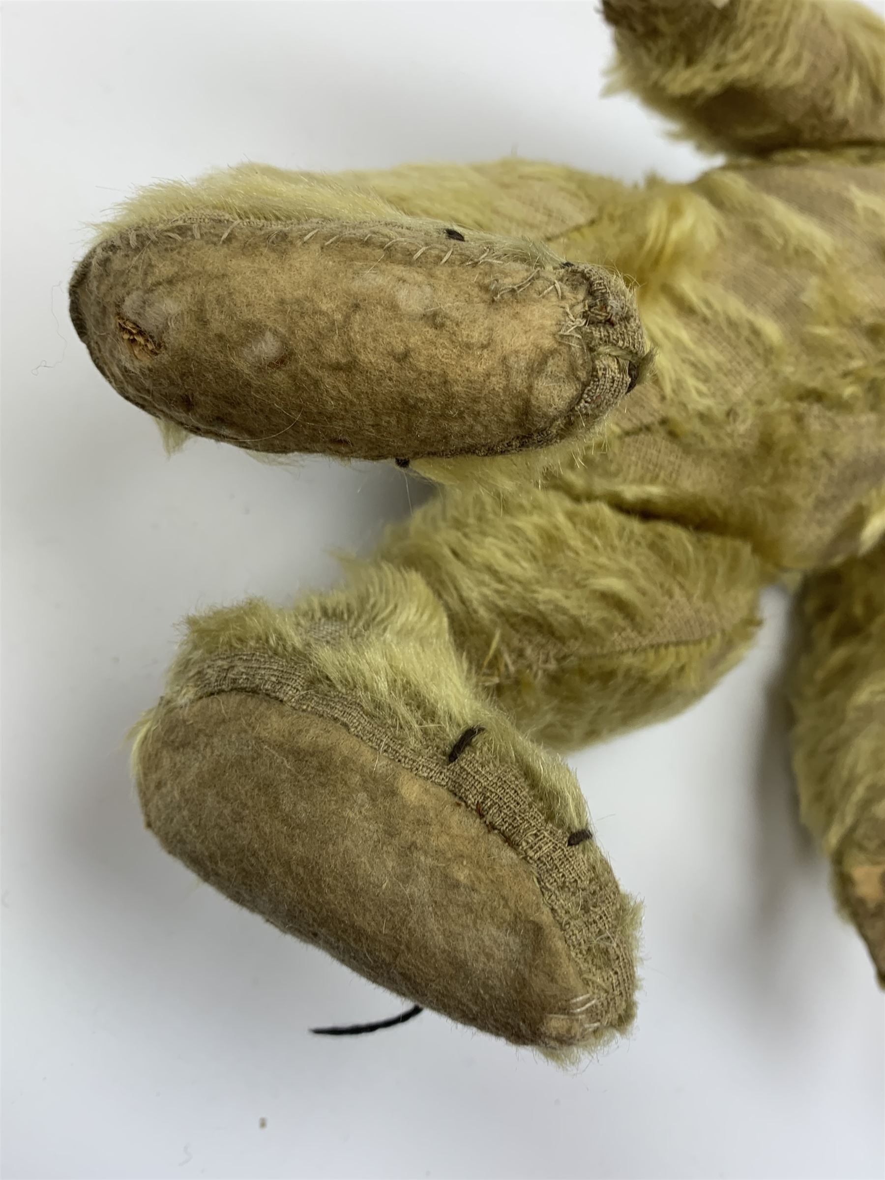 Early 20th century English teddy bear, with wood wool filled body with jointed limbs, felt covered paw pads, five claw stitching to feet and elongated arms with spoon shaped paws H14