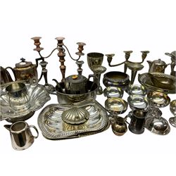 Large quantity of mostly silver plate, to include various teawares including a squat teapot with embossed foliate decoration, hot water pots, milk/cream jugs, plus dishes of various size and form, warming dish stand, entree dish with inserts, candelabra and candlesticks, bud vases, etc. 
