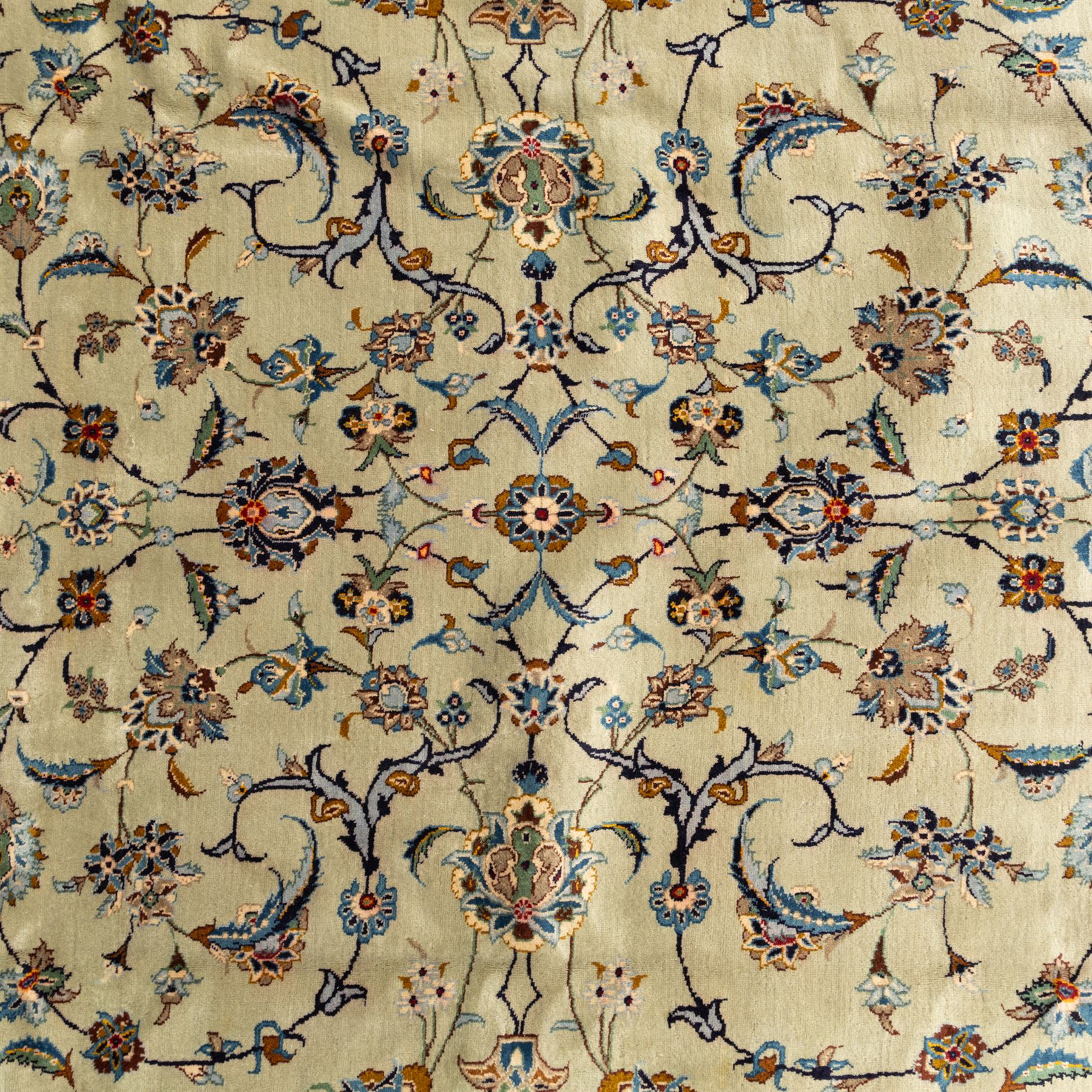 Persian Kashan rug, cream ground decorated with an all-over pattern of interlaced floral stems, rosettes and palmettes in blue, gold and rust tones, framed by layered floral borders, woven in the Kashan region of Iran