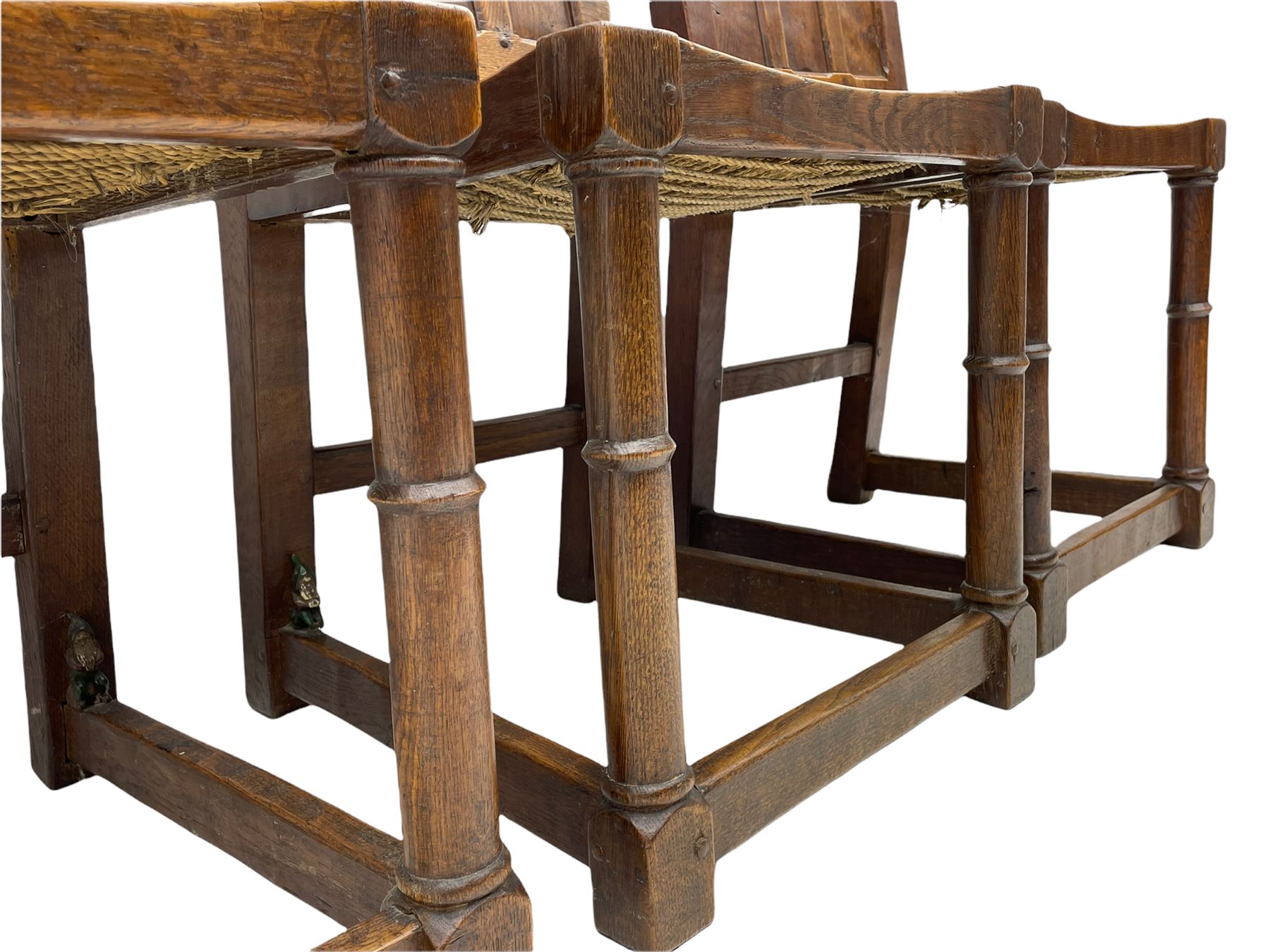 'Gnomeman' set of three oak dining chairs, panelled backs over curved seat rails with drop in rope rush seats, turned front supports with collar joined by plain stretchers, two with carved seated gnome figures, painted

Provenance - This collection of early 'Gnomeman' furniture comes to us directly from the Whittaker family. The pieces were made by the vendor's father Thomas Whittaker in the 1930/40s for his own use. During this time, he lived in York and made items for himself and friends. Whittaker adopted the gnome as a signature and trademark after his move to Littlebeck, Whitby.