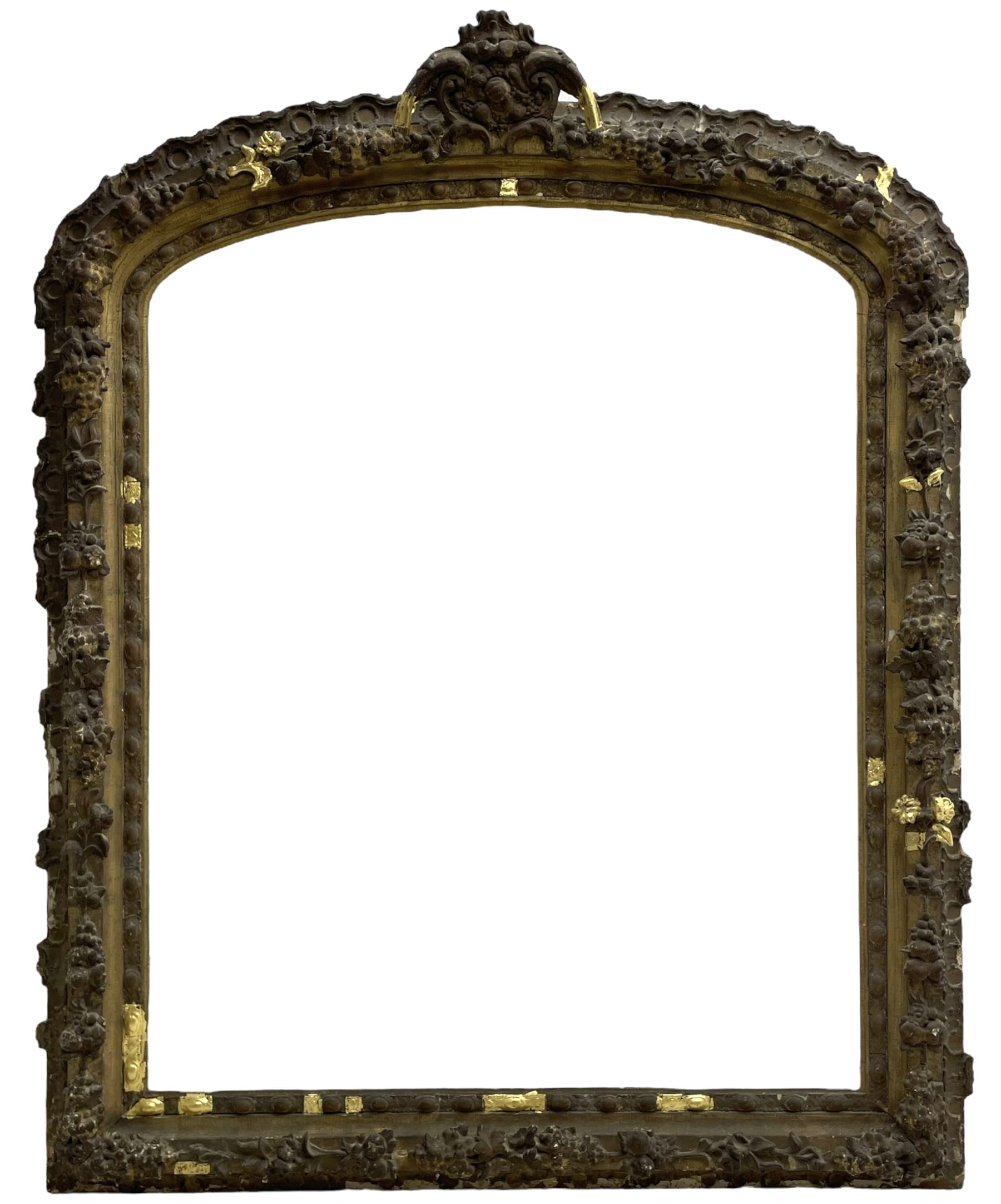 19th century giltwood and gesso moulded picture or mirror frame, the arched cresting rail mounted by central cartouche decorated with foliate scrolls and fruit, the outer frame decorated with scalloped edge and shell mouldings, trailing foliage with flower head and fruit to the central band, egg and dart moulded inner slip