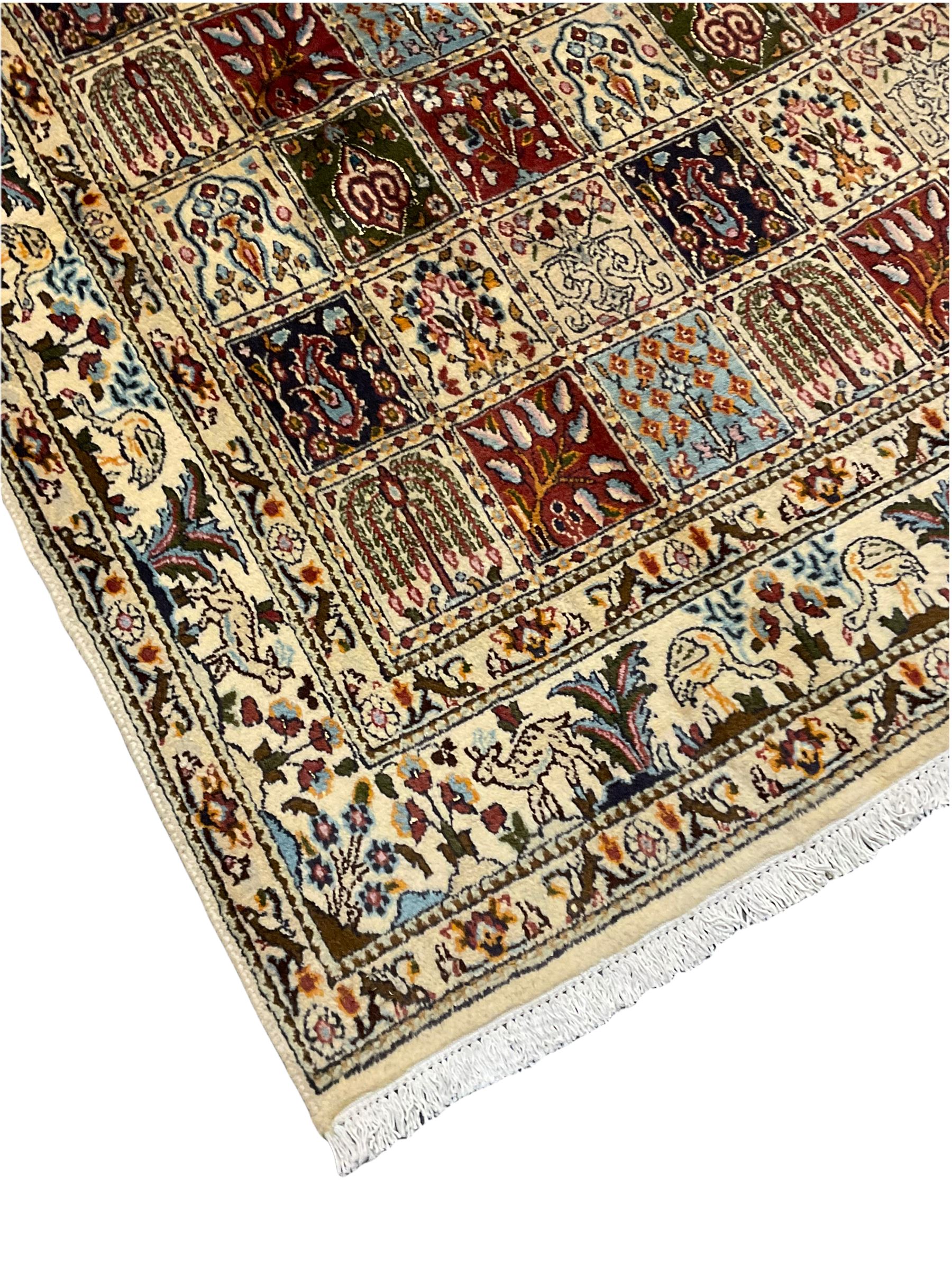 Persian Heriz design rug, ivory ground with rectangular panels each depicting garden scenes of tree of life, plants and Boteh motifs, the guarded border decorated with wildlife and bird scenes
