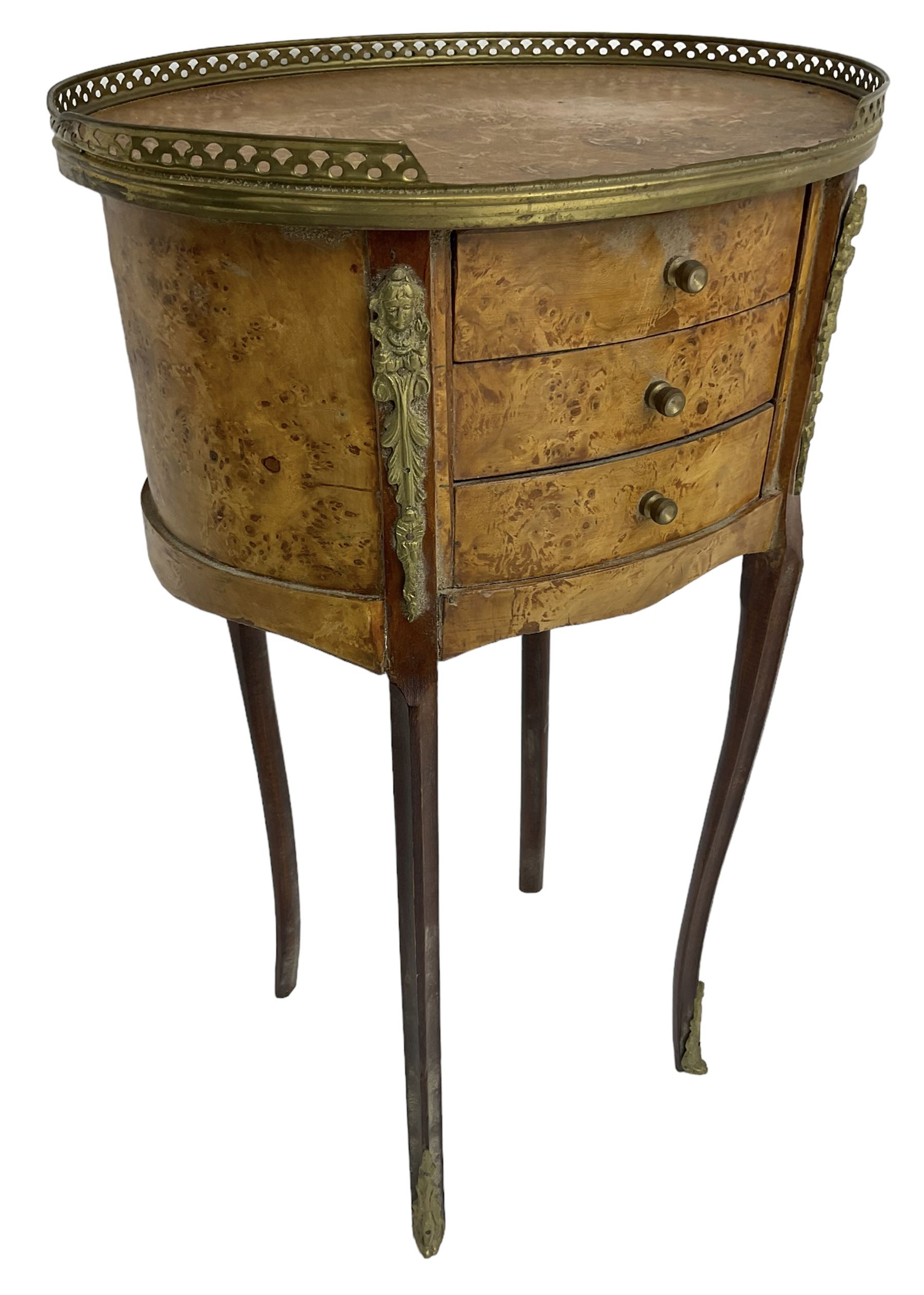 Late 20th century French design figured elm and bedside table, raised pierced gilt metal gallery over oval top, fitted with three mahogany lined drawers flanked by gilt metal mounts of female mask and foliate form, on cabriole supports