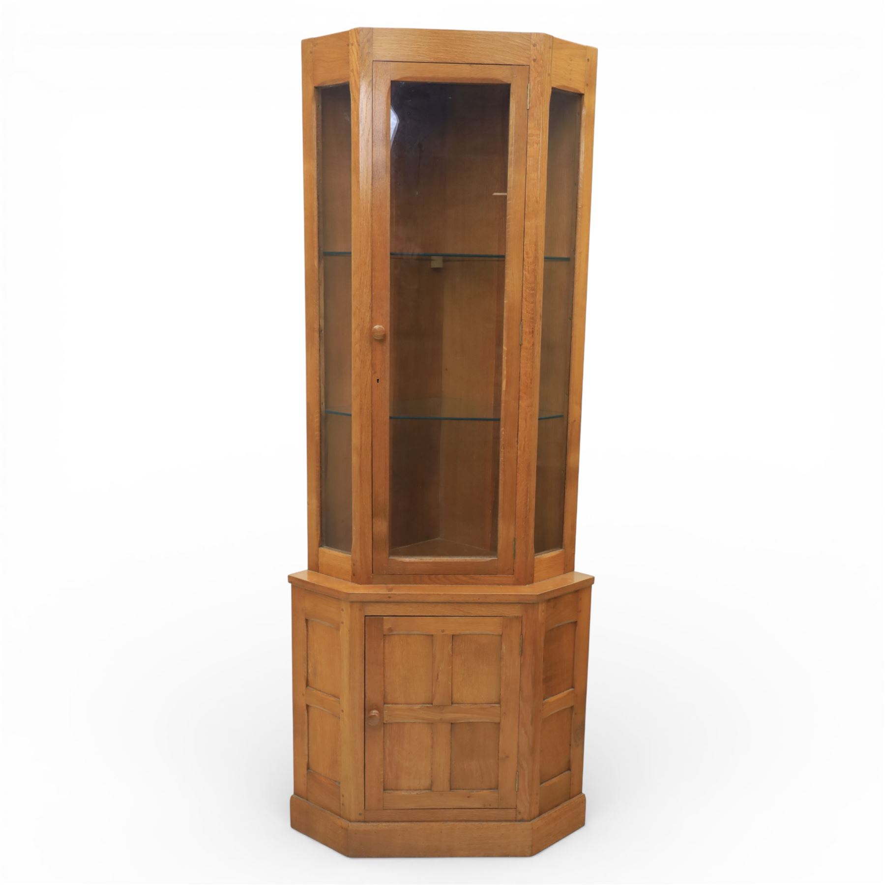 Cat & Mouseman - oak corner cabinet, glazed door with two fixed glass shelves, above a panelled door and sides raised on a plinth base, with cat and mouse carving to the lower side by Lyndon Hammell a former apprentice of Robert 'Mouseman' Thompson