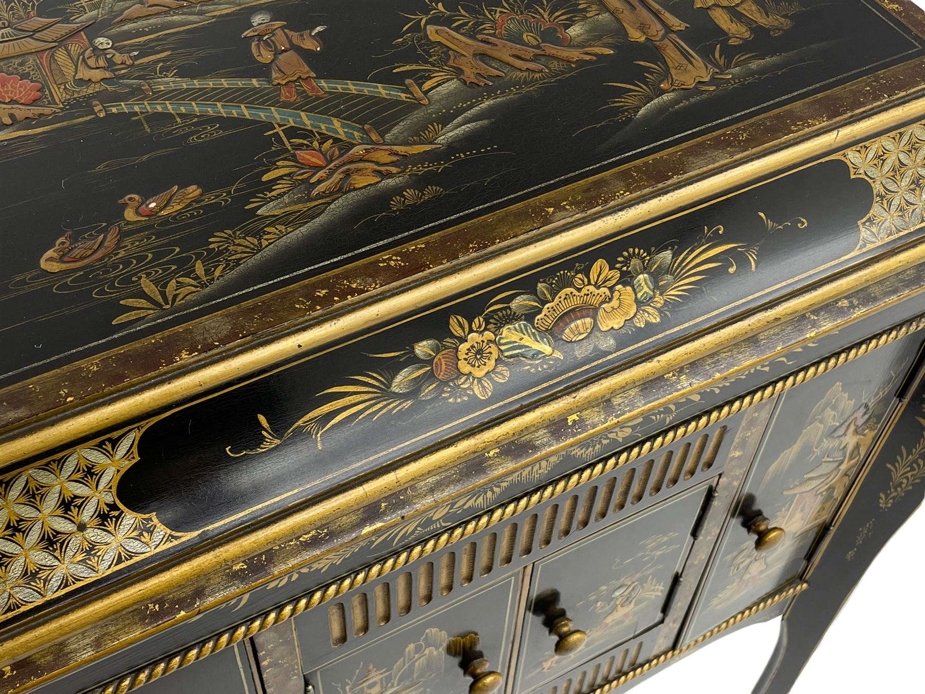 Early 20th century Chinoiserie lacquered gramophone cabinet, the lid decorated with raised gilt work, traditional landscape and figural scenes, fitted with 'Apollo' 'No. 114' gramophone, cupboards below, on cabriole supports