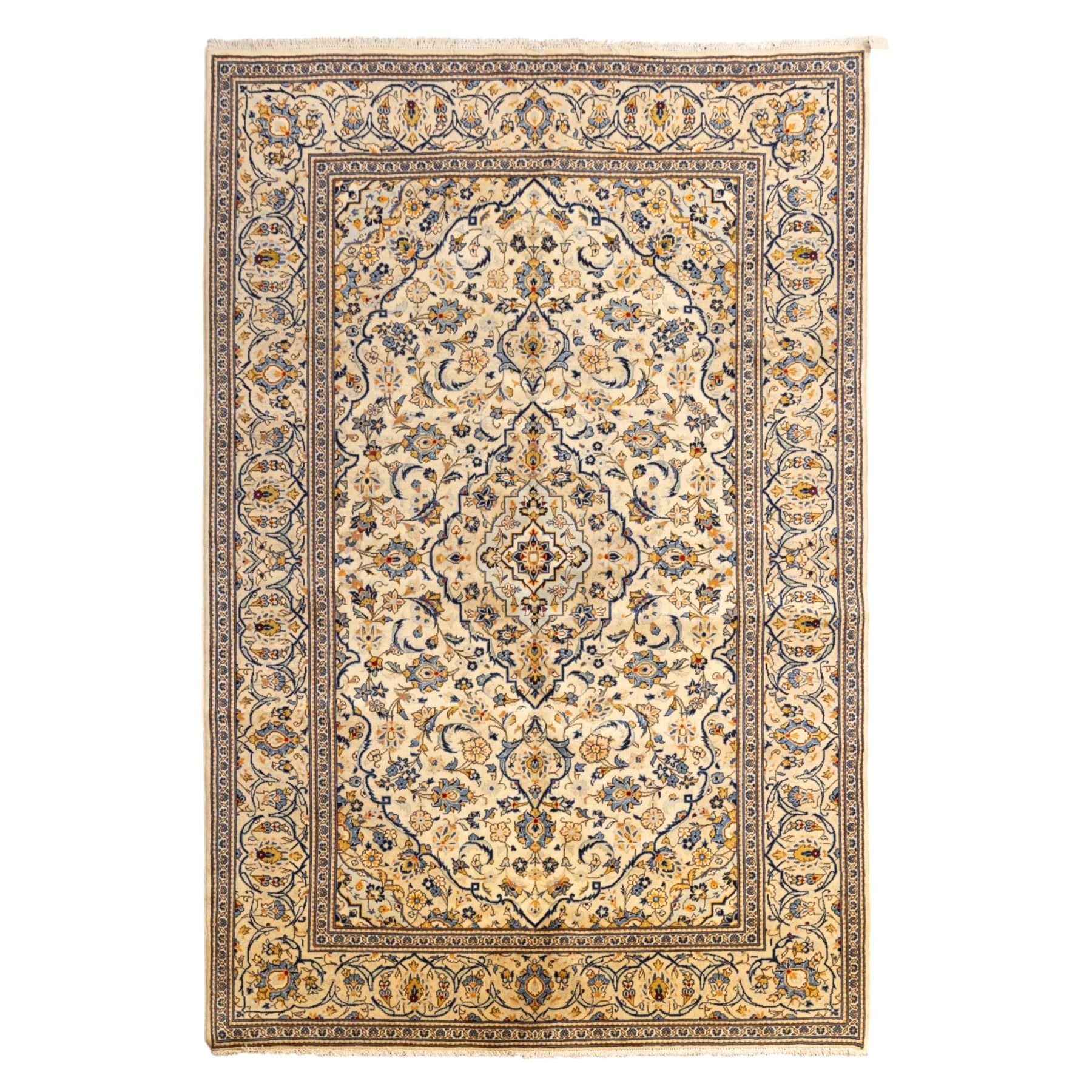Central Persian Kashan hand-knotted carpet, ivory ground with central stepped floral medallion surrounded by scrolling vine work, palmettes, and stylized blossoms, field enclosed by a multi-border arrangement, wide main border decorated with repeating floral cartouches and foliate motifs, flanked by narrow guard stripes, with cotton fringe ends