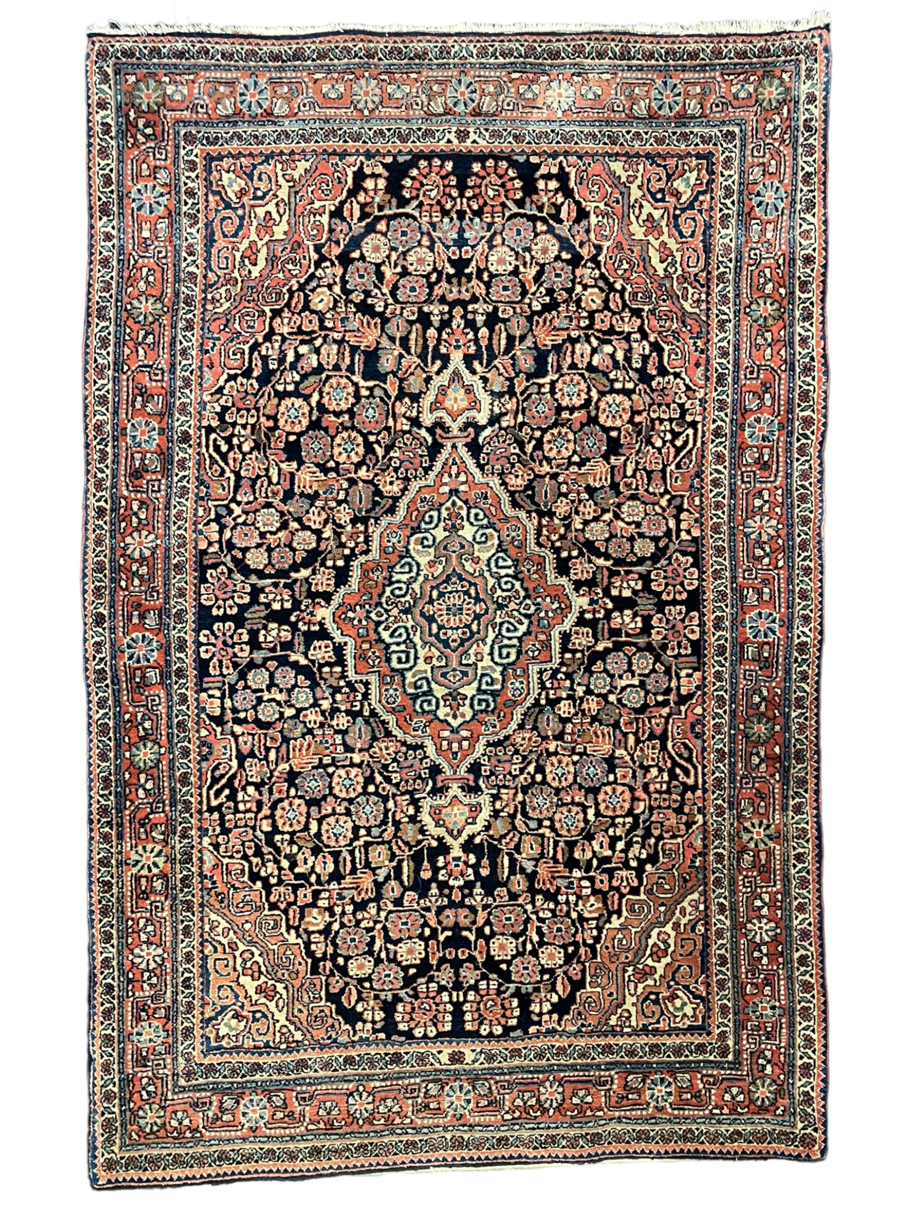 Persian indigo ground rug, the field decorated with intricate interlaced foliage branches and small flower heads, shaped floral design central medallion, the border decorated with scrolling branch and flower heads within guard bands 