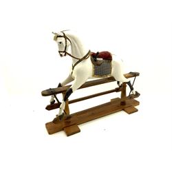 Victorian white finished rocking horse, complete with studded saddle and bridle, brass stirrups and rockers, raised on two turned columns and floor stretcher 