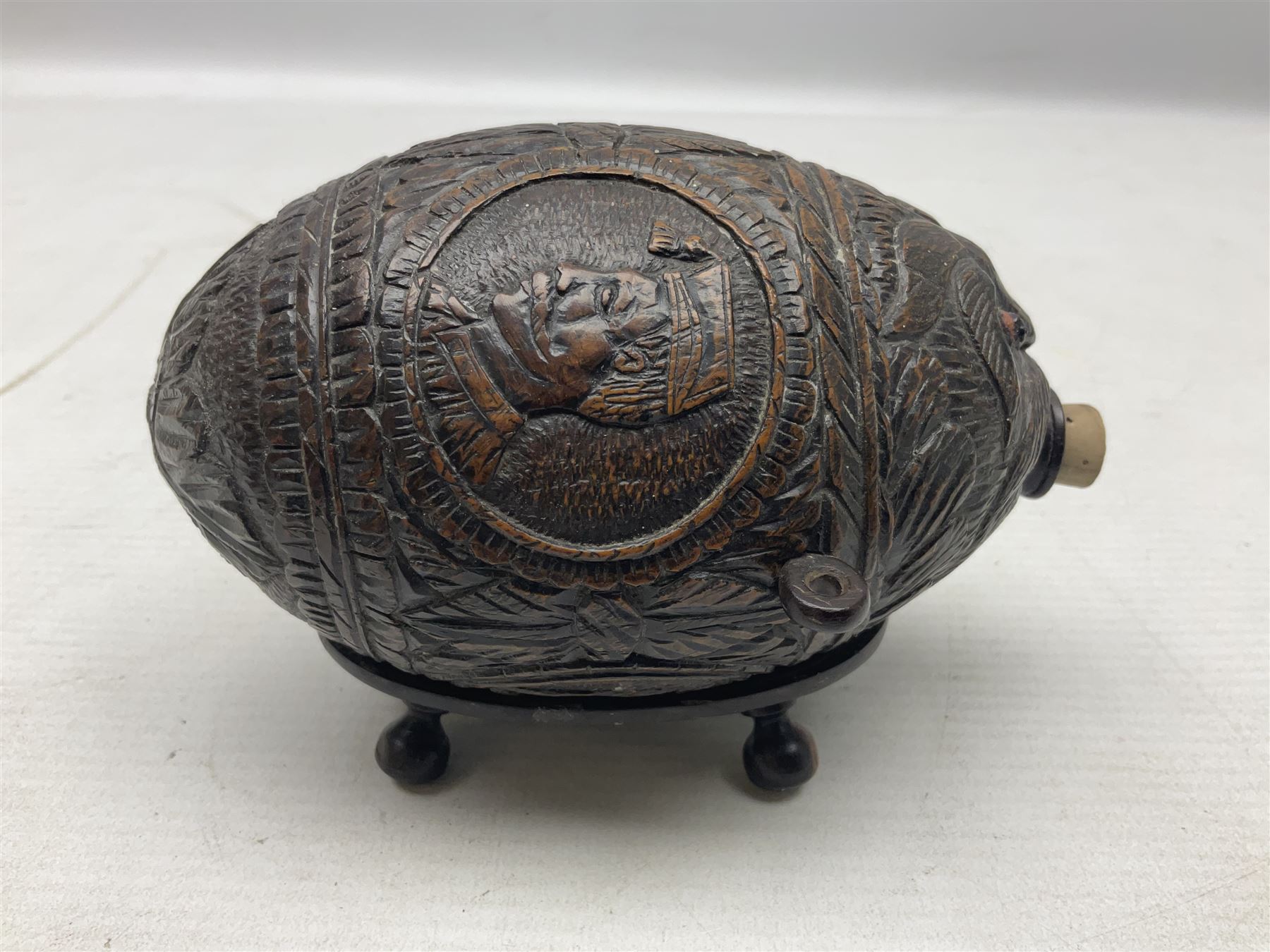 19th century bug bear flask carved with Balkan figures, a wolf and leafage with glass eyes, L14cm on stand 