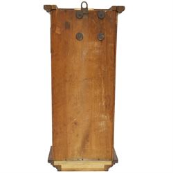Art Deco style oak wall clock, moulded cornice above a silvered dial with Arabic numerals and geometric spandrels, glazed door with geometric bevelled glass panels enclosing a circular pendulum, on a stepped moulded base