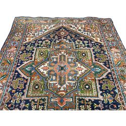 Persian Heriz indigo and rust ground rug, central geometric star medallion decorated with stylised foliate motifs, the border decorated with stylised flower heads
