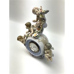 A Lladro mantel clock modelled as a globe with inset clock, surmounted by four putti and floral garlands, with blue printed mark and impressed 5973 beneath, H29cm.