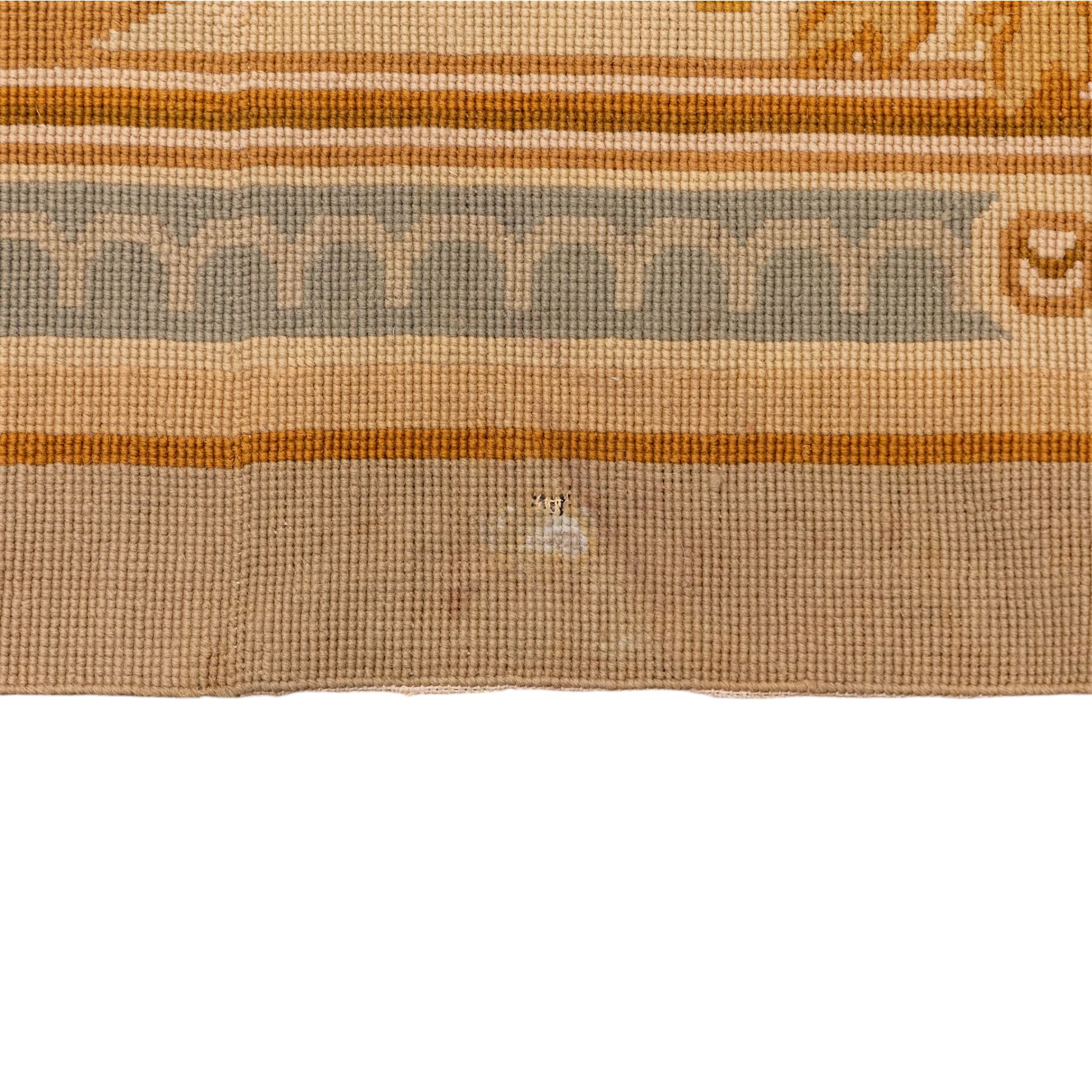 20th-century Aubusson-style woven tapestry wall hanging of rectangular form, the design with a central oval floral medallion composed of delicate sprays in soft pinks, creams, and muted green enclosed by an elaborate dark blue scrolling acanthus ground enriched with foliate ornamentation, field framed by floral cartouches to the corners and multiple guard borders in pale blue, ivory, and ochre tones