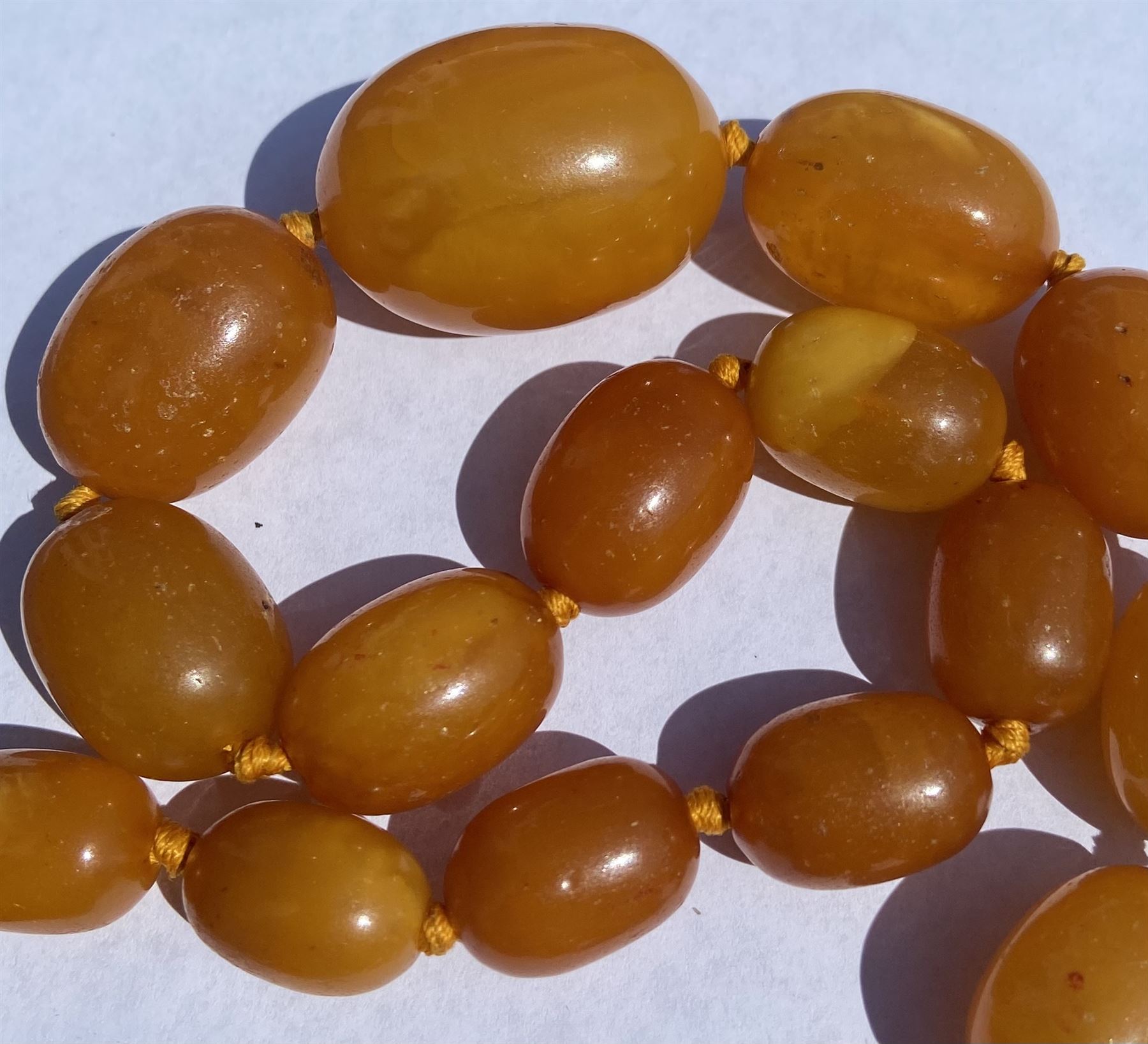 Single strand graduating oval butterscotch amber bead necklace, with three additional loose amber beads