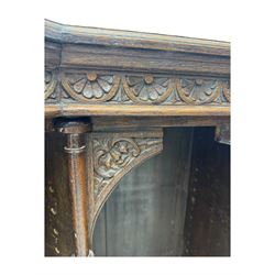 Victorian carved oak corner bookcase, L-shaped form, moulded top over lunette carved frieze, decorated with S-scroll and mask carved corbels with trailing acanthus leaves, fitted with adjustable shelves, on moulded plinth base 